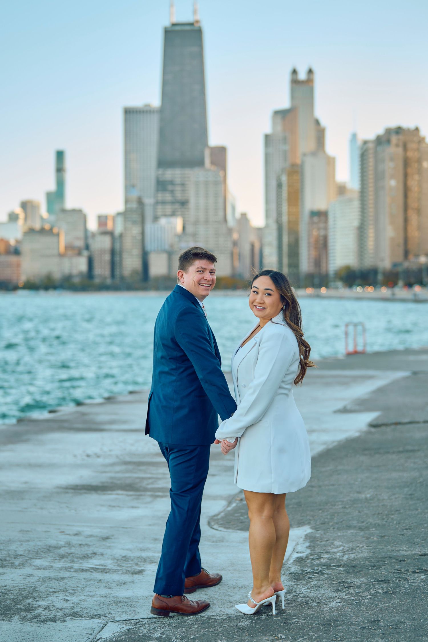 A couple poses together on Chicago's lakefront with the iconic John Hancock building and skyline in the background.