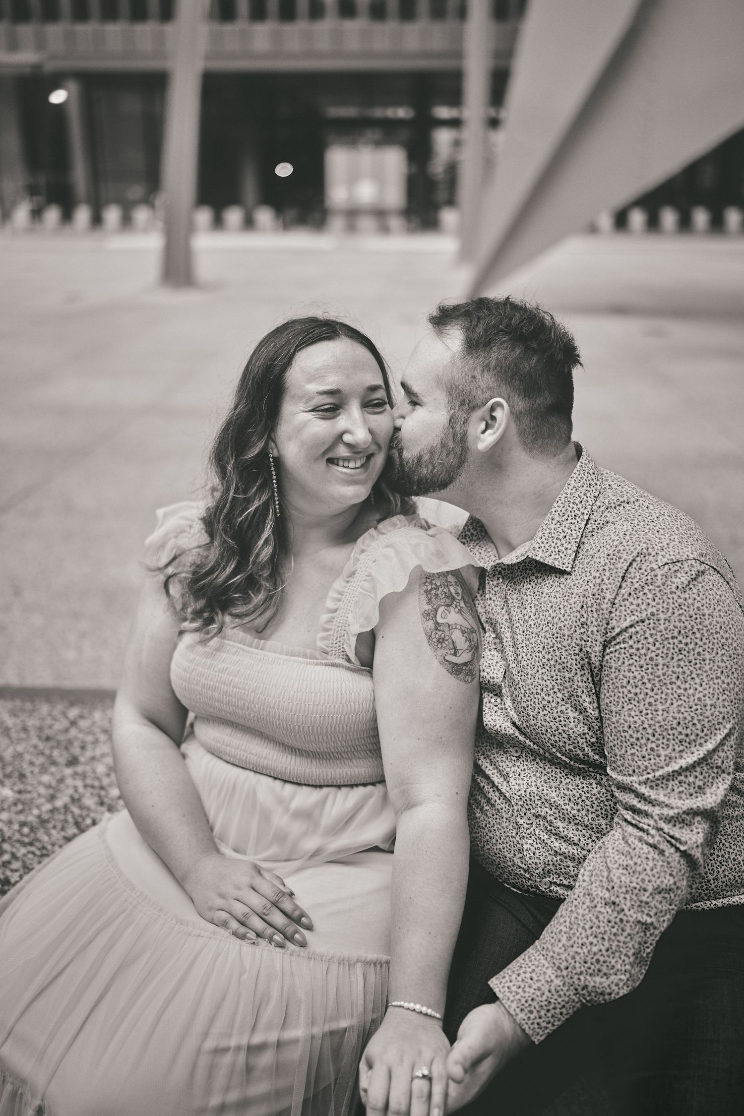 A romantic black and white portrait of a couple sharing an intimate moment outdoors in casual attire.