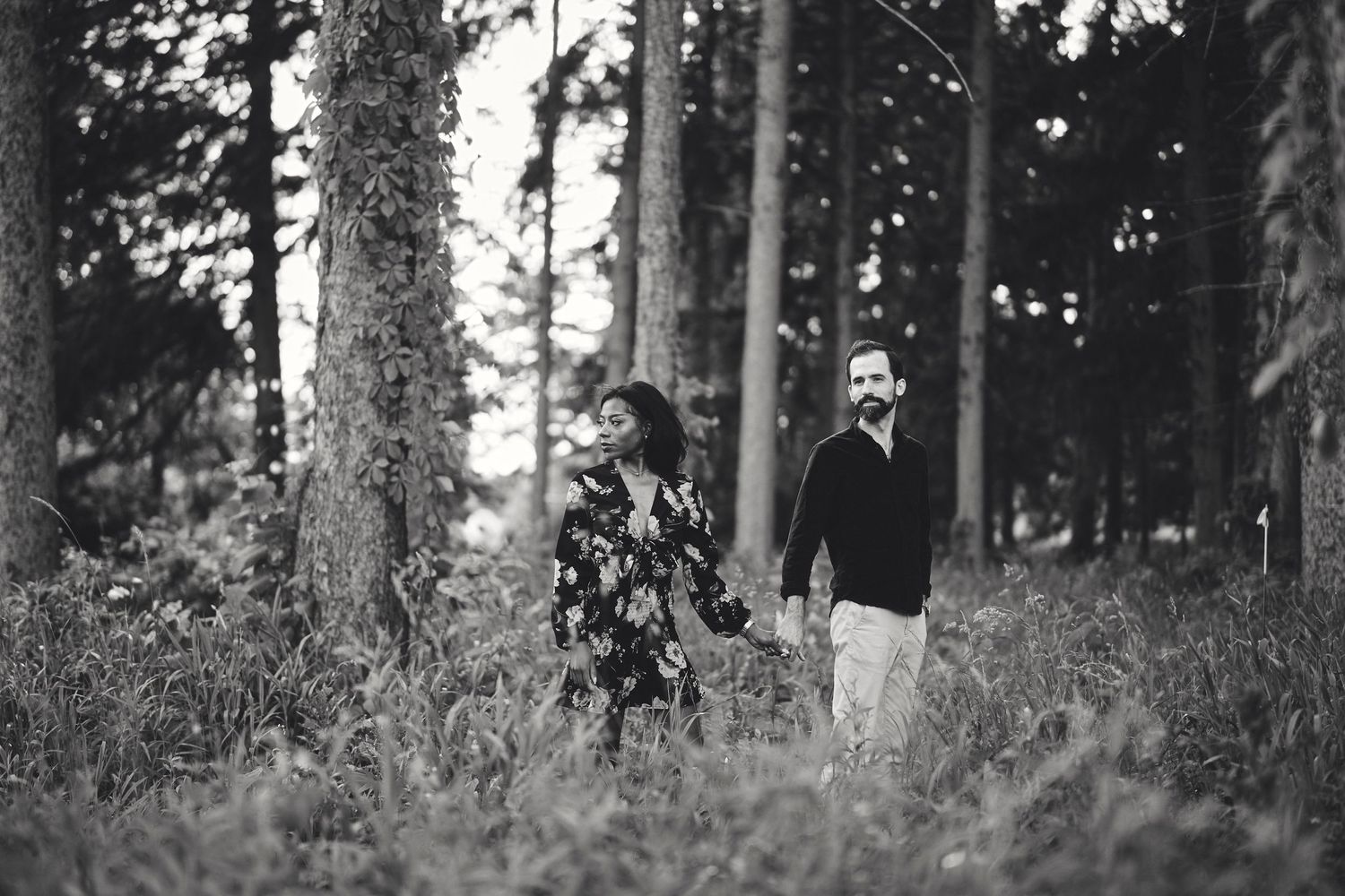 Two figures walking together through a misty forest captured in black and white photography.