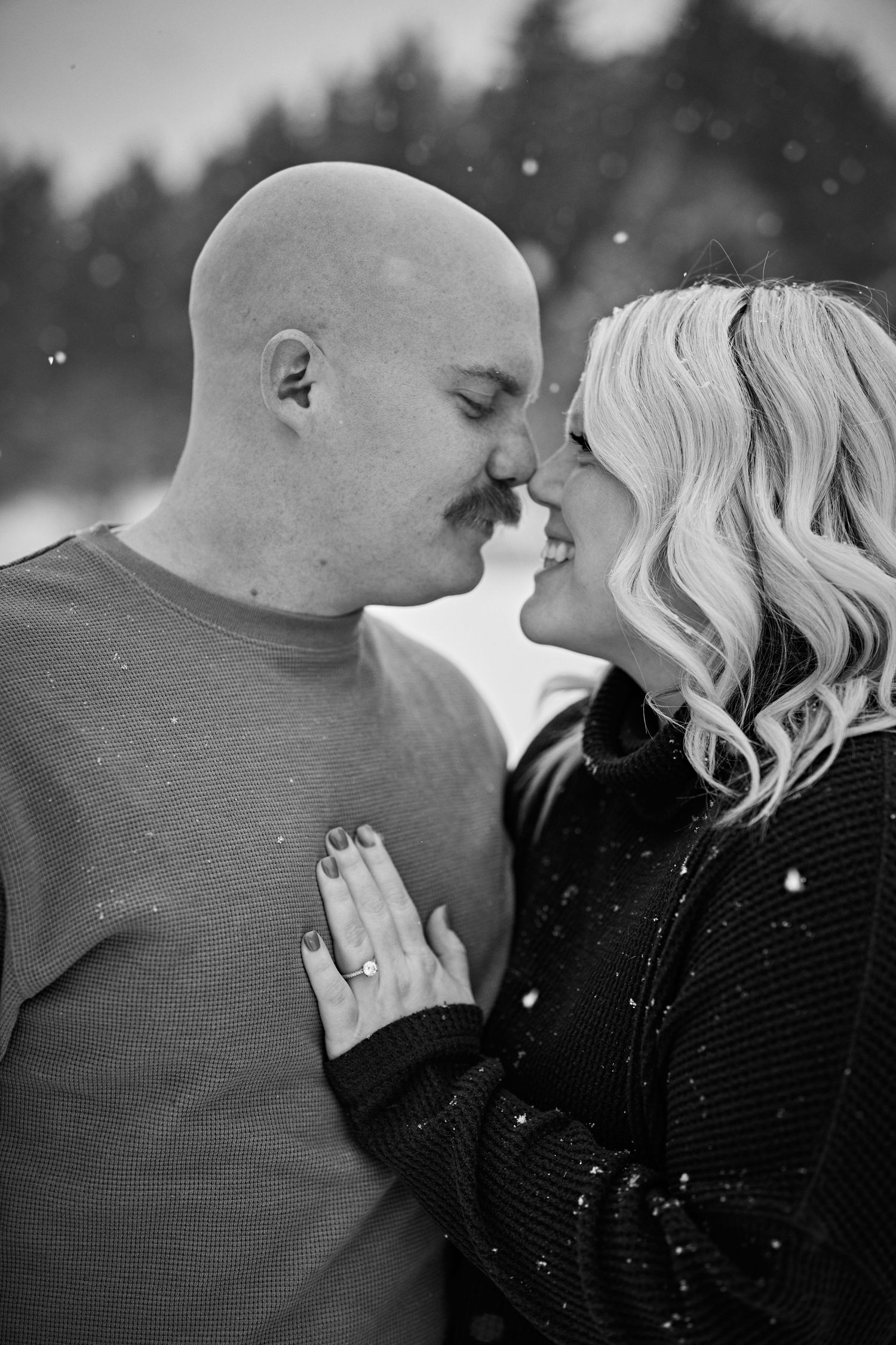A romantic black and white photo shows a couple sharing an intimate moment in the falling snow.