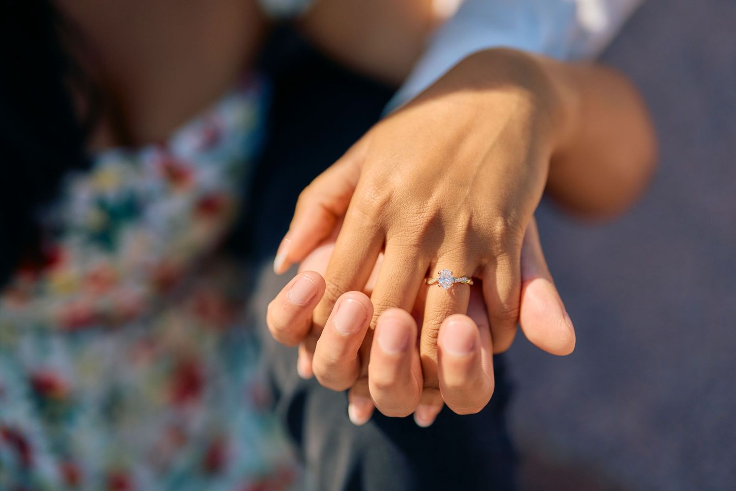Close-up of clasped hands with gold wedding rings showing on fingers.