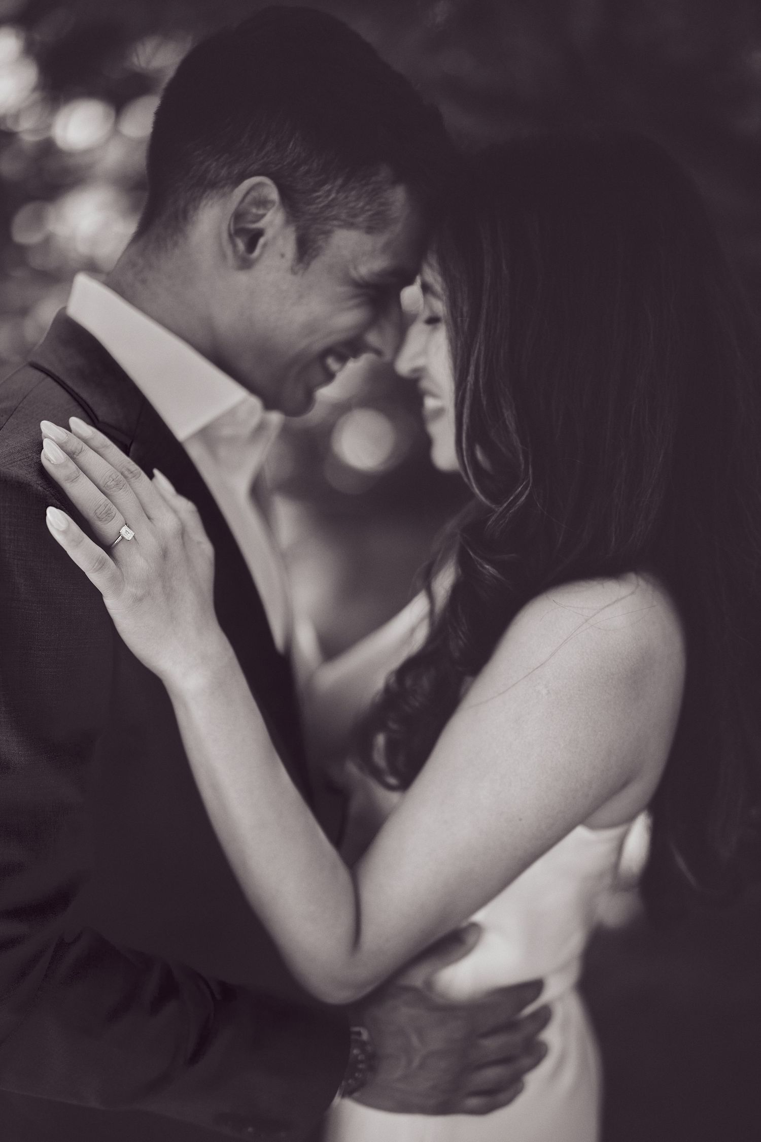 A romantic black and white portrait of a couple in formal attire sharing an intimate moment during a dance.