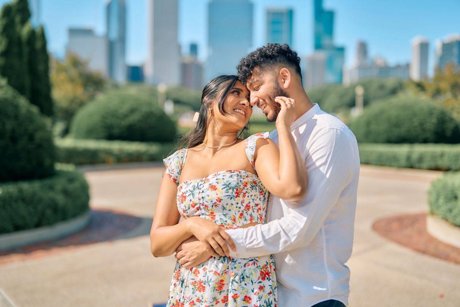 A loving couple shares an intimate moment in a park with Chicago's skyline visible in the background.