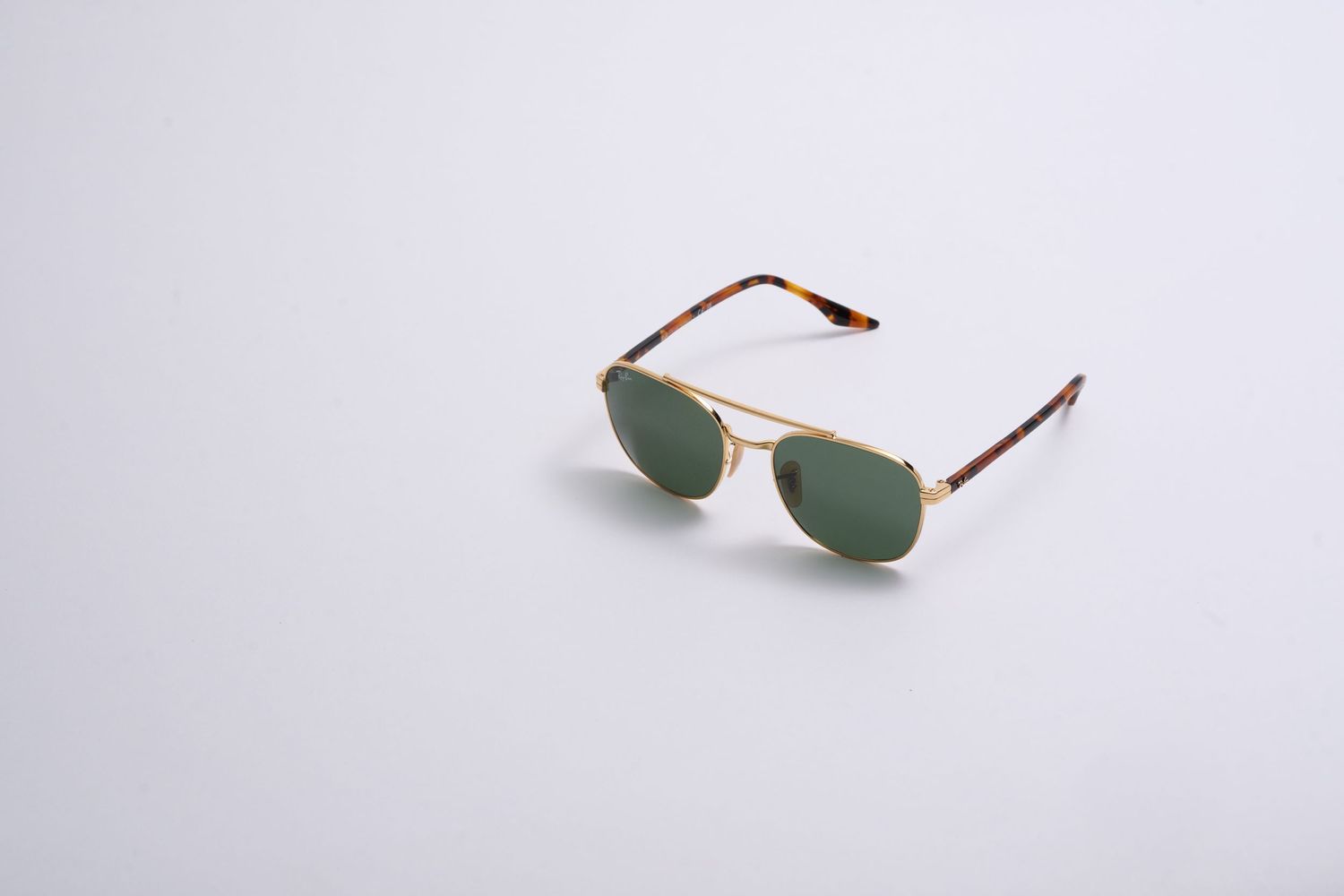 Gold-framed aviator sunglasses with green lenses isolated on white background.