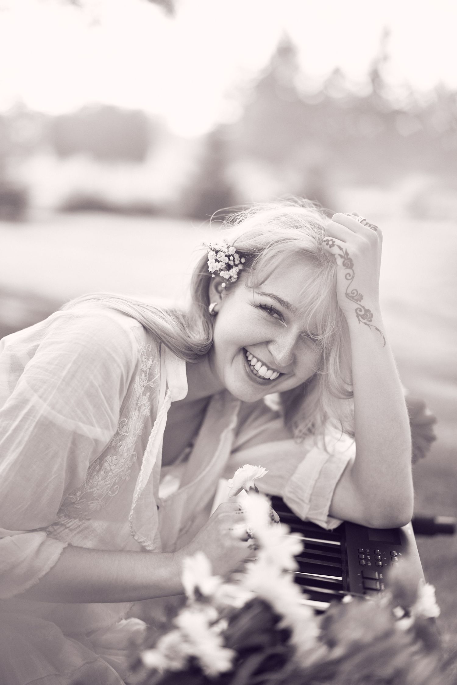 A person in a white top lies in a grassy field while smiling and enjoying a bright summer day.