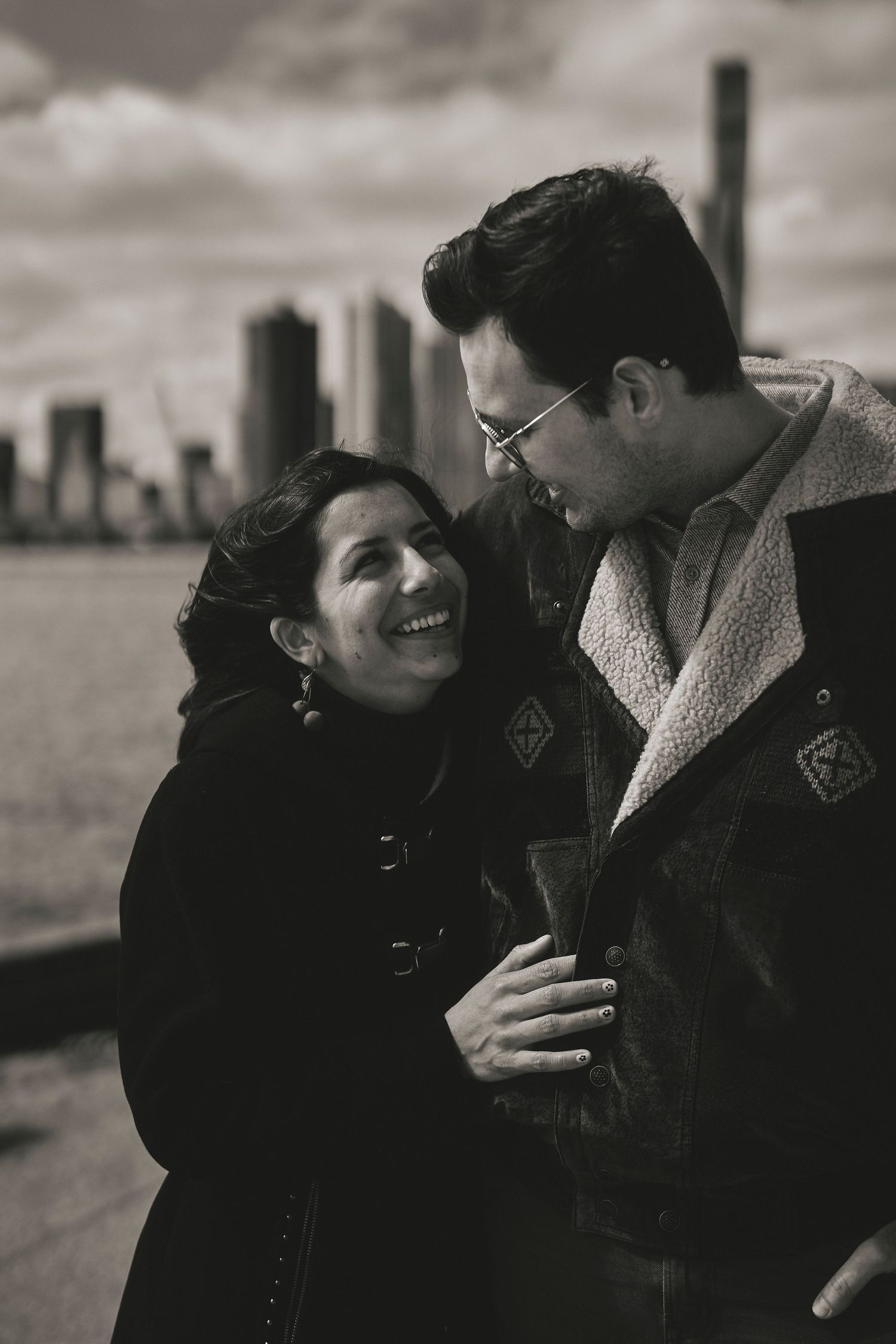 Black and white romantic portrait of a couple sharing an intimate moment with city skyline in the background.