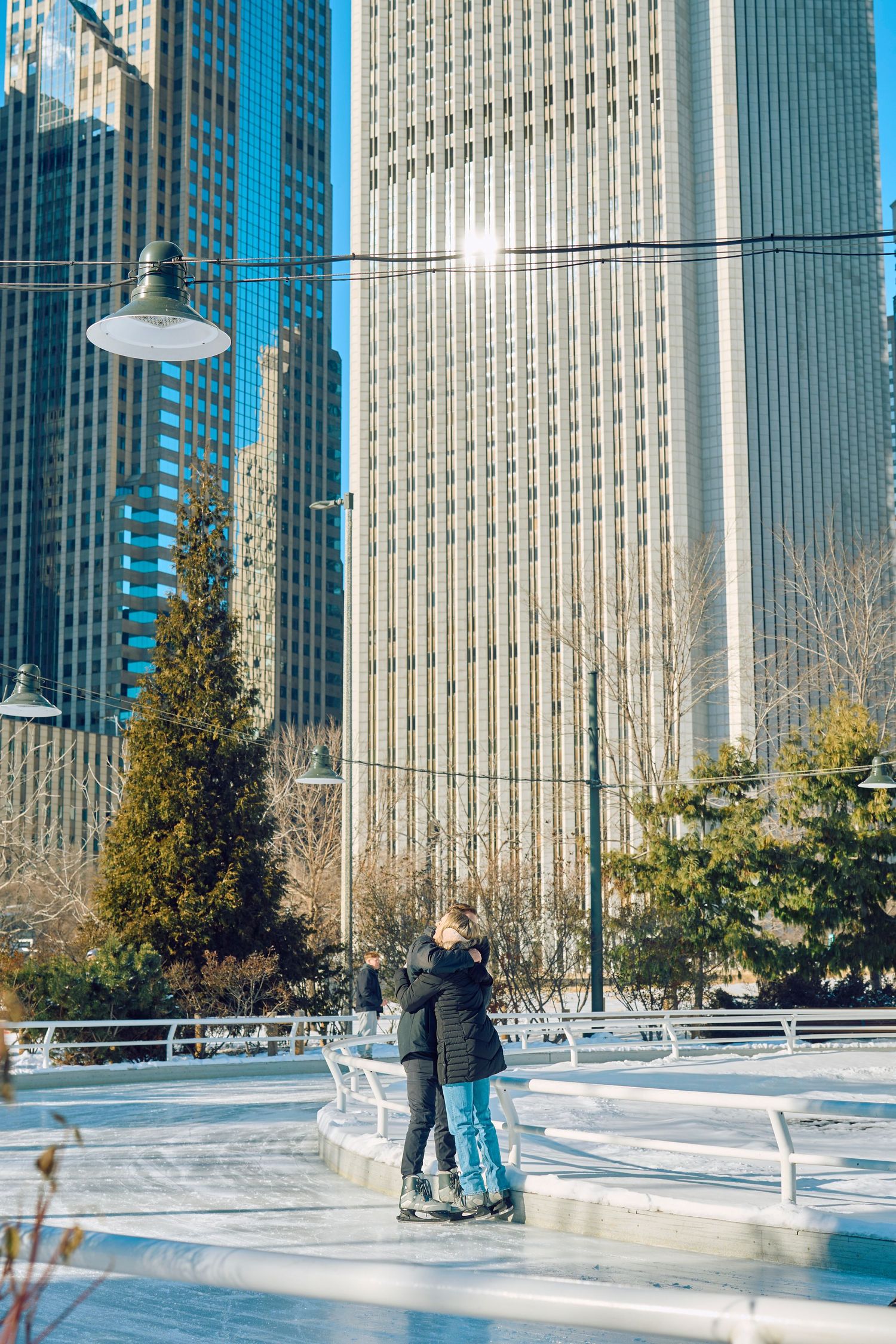 Ice skaters enjoy winter activities at an outdoor rink surrounded by tall city skyscrapers and trees in downtown Chicago.