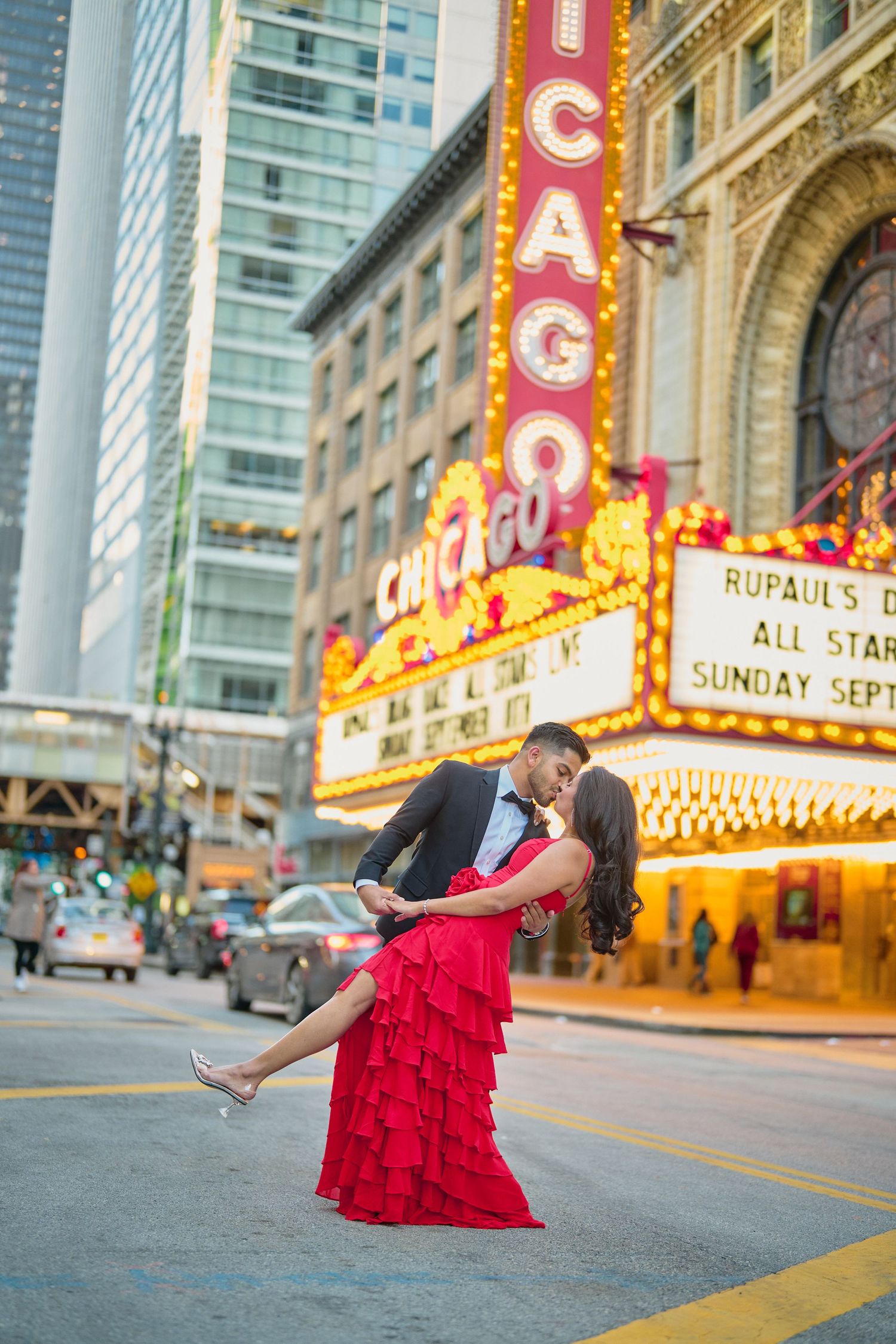 Romantic couple dances in front of illuminated Chicago Theatre marquee at dusk on State Street.