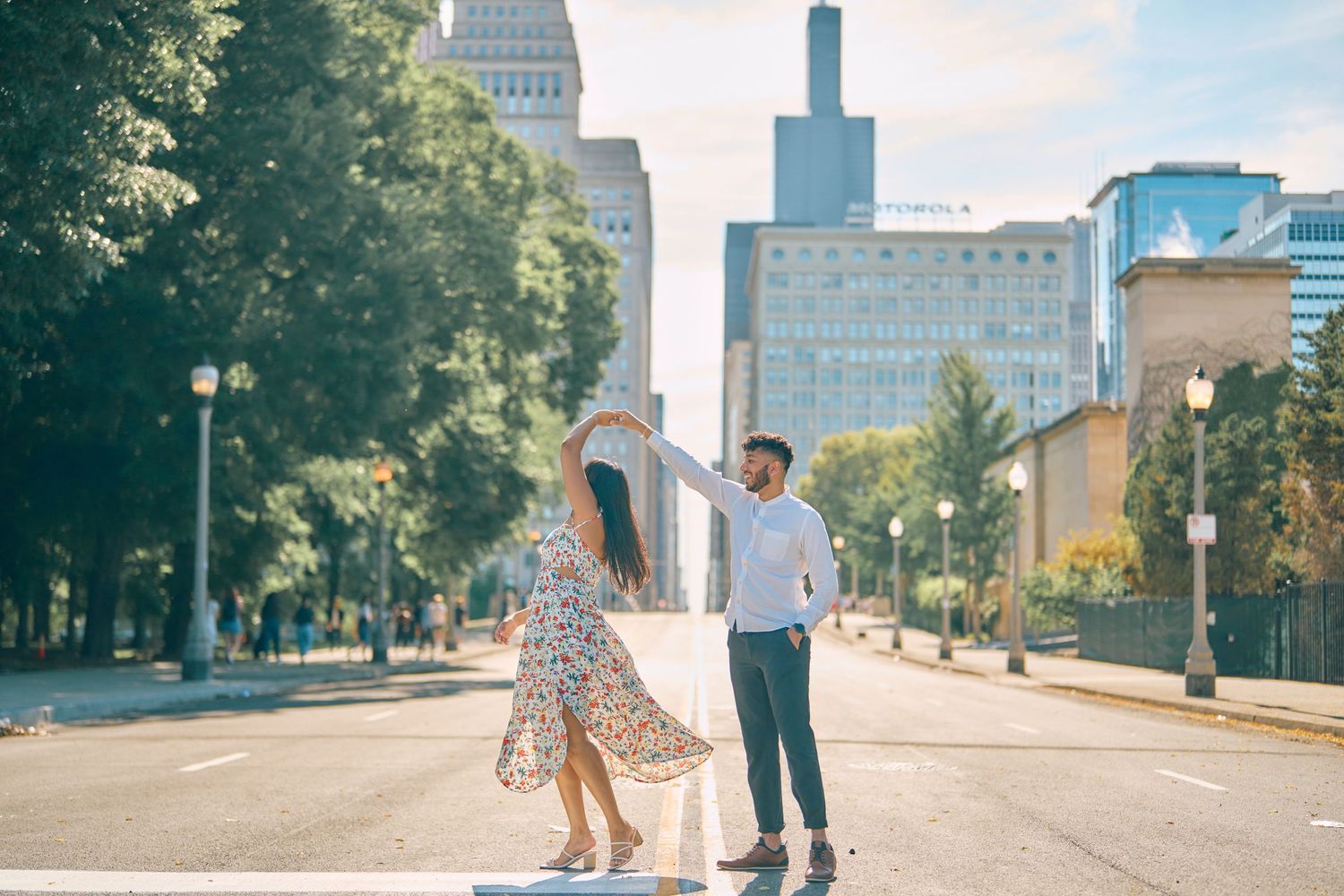 Couple enjoys a sunny day dancing on an urban street with Chicago skyscrapers and Willis Tower in background.