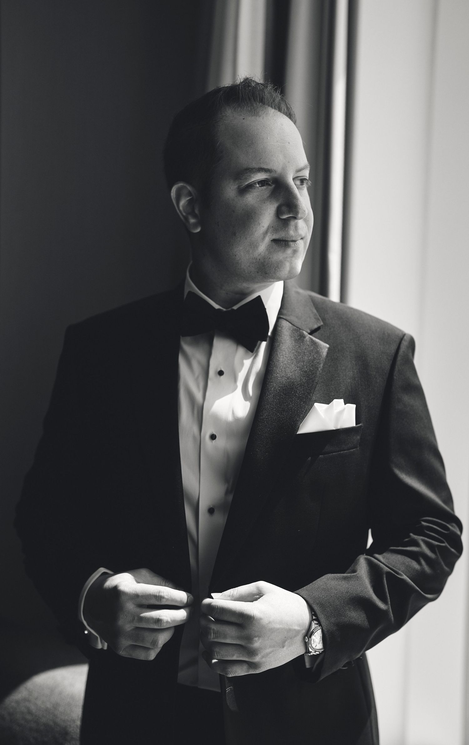 A groom in a black tuxedo and white shirt adjusts his cufflinks in a series of black and white photos.
