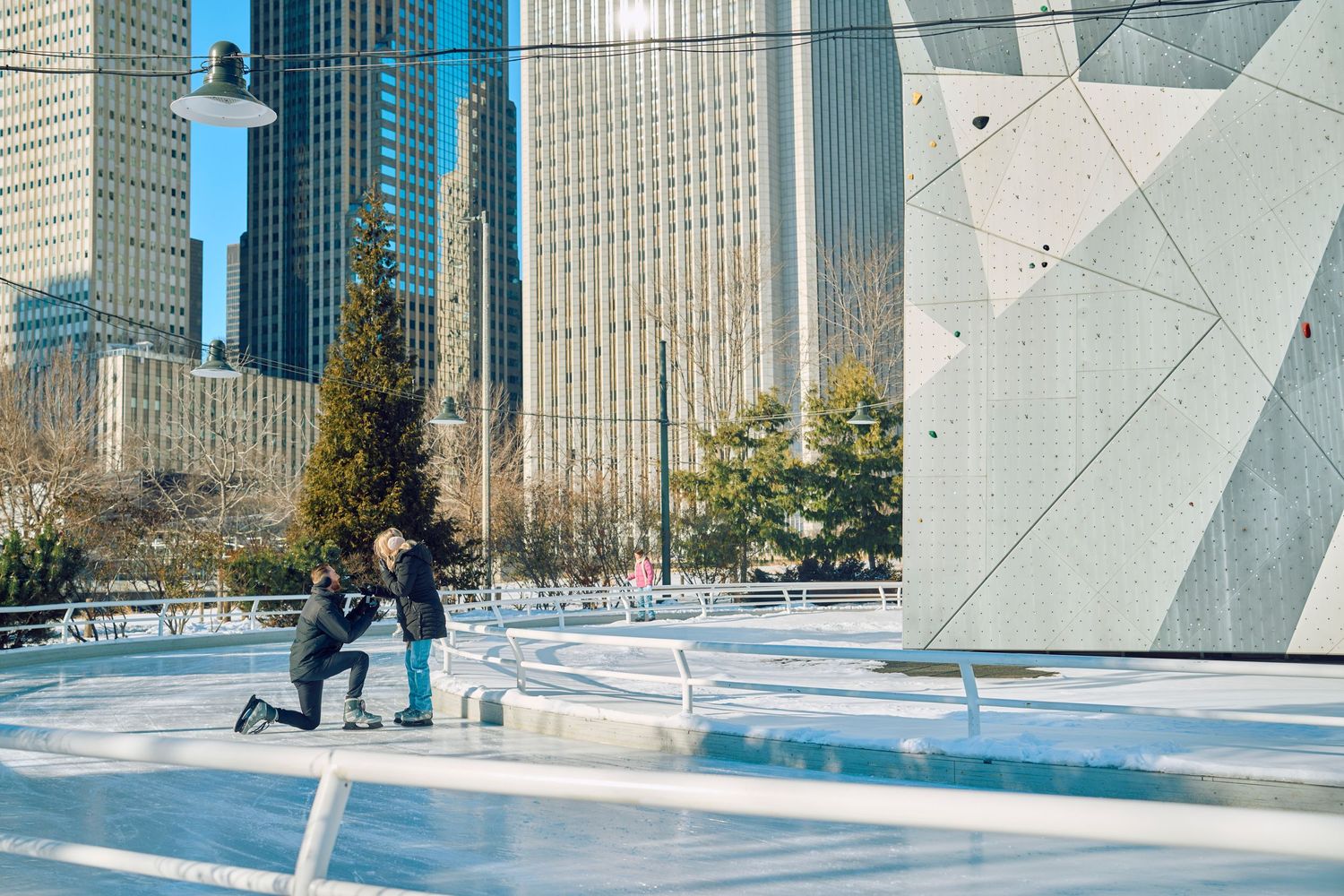 People skating at the downtown Chicago ice rink with modern architectural buildings and glass structures in the background.