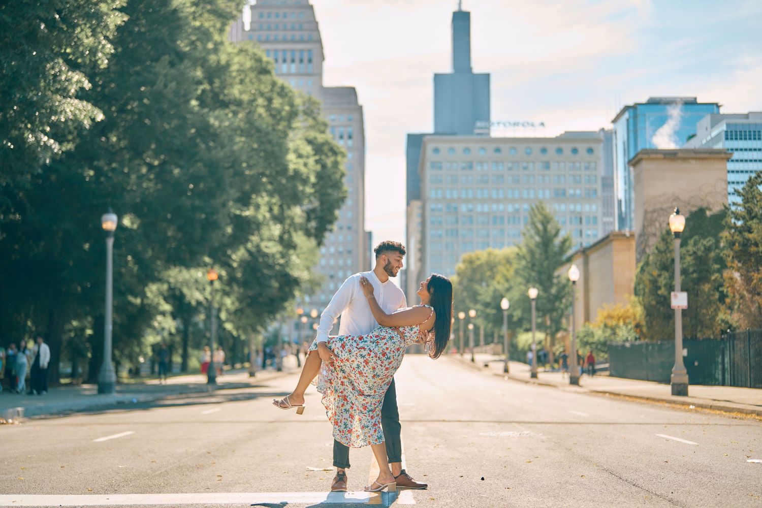 Couple dancing together on an urban street with skyscrapers and trees in downtown Chicago on a sunny day.
