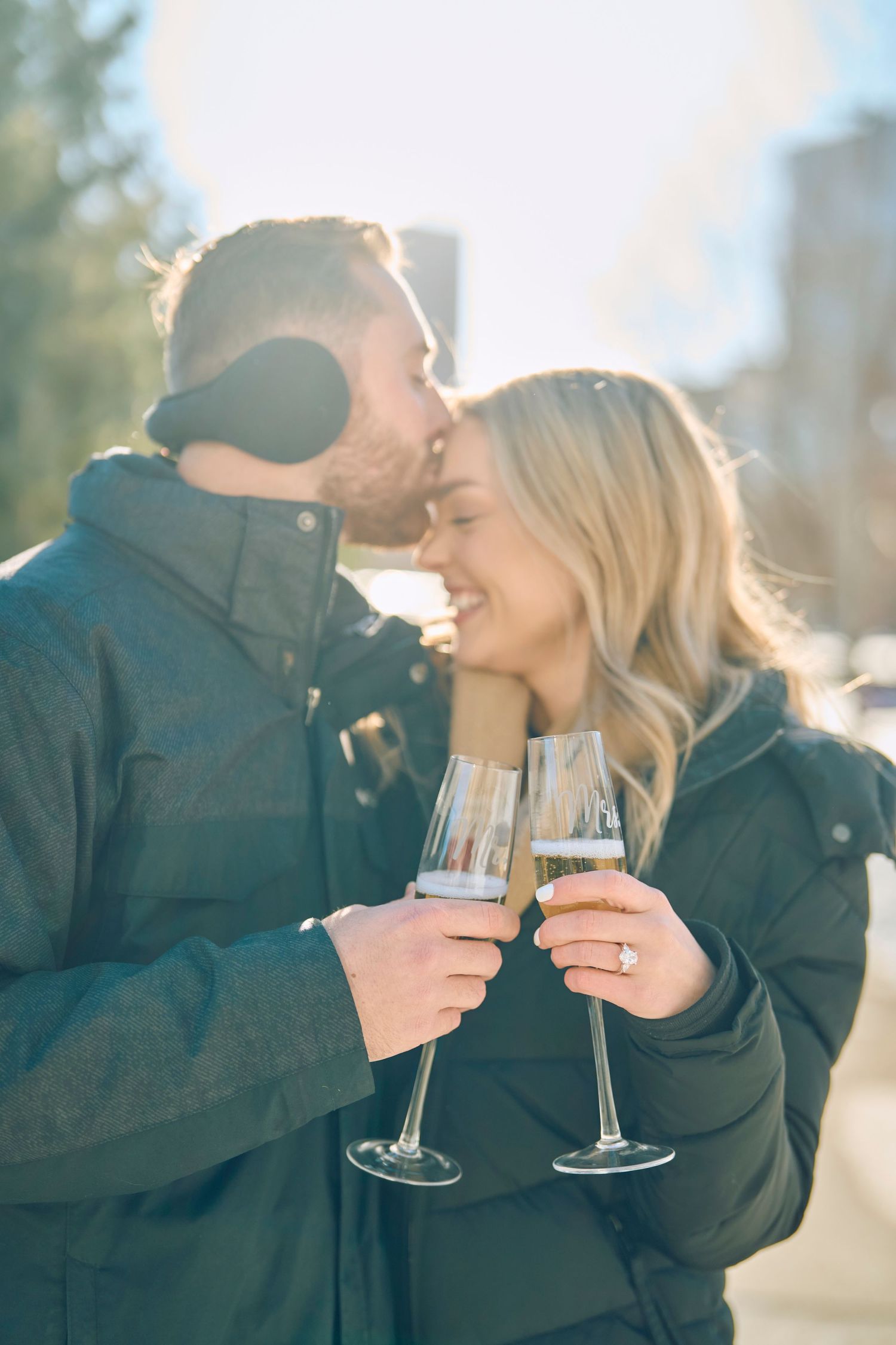 Couple shares champagne and an intimate moment outdoors on a sunny winter day.