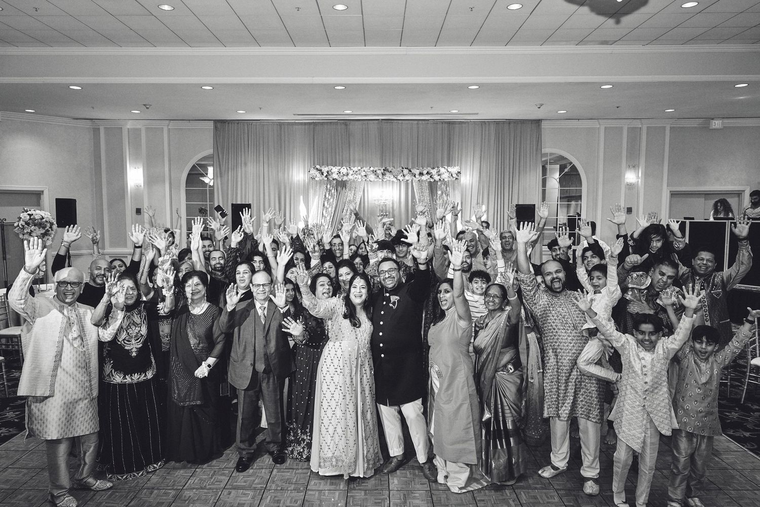 Large group celebration photo in an elegant ballroom with white draping.