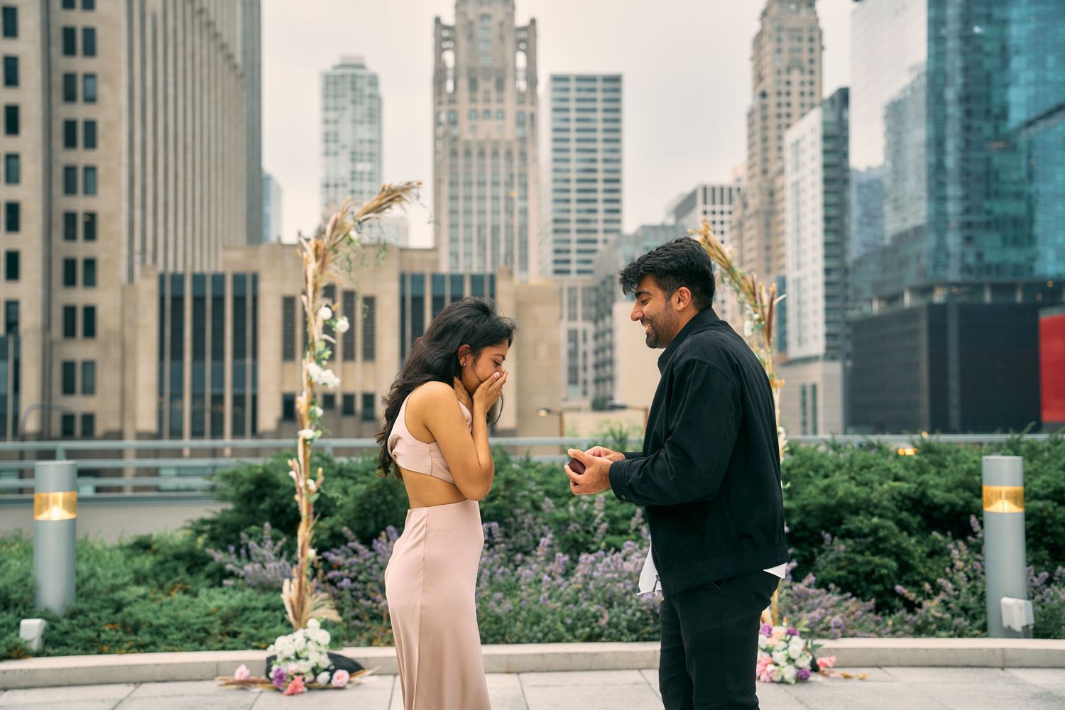 A couple shares a romantic moment at a rooftop garden in Chicago with the iconic Michigan Avenue skyline in the backdrop.