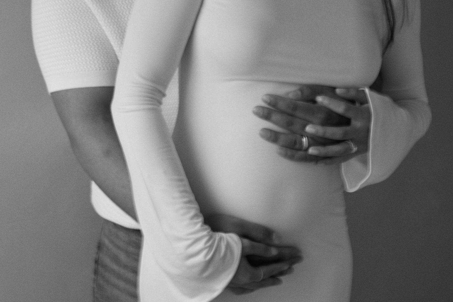 Black and white photo showing someone in a white long sleeve shirt holding their stomach in discomfort or pain.