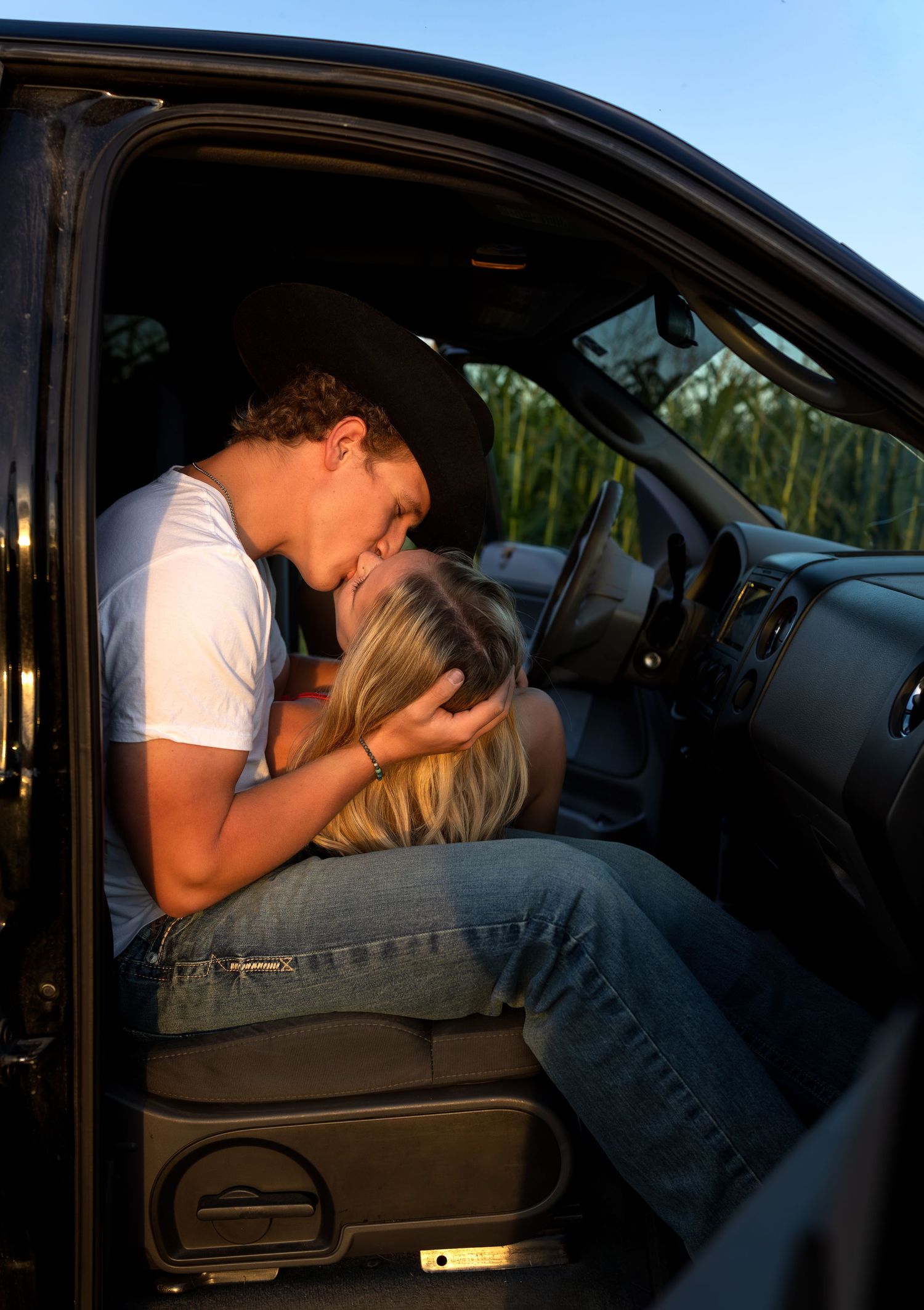 A young couple snuggle up and kiss in a pickup truck