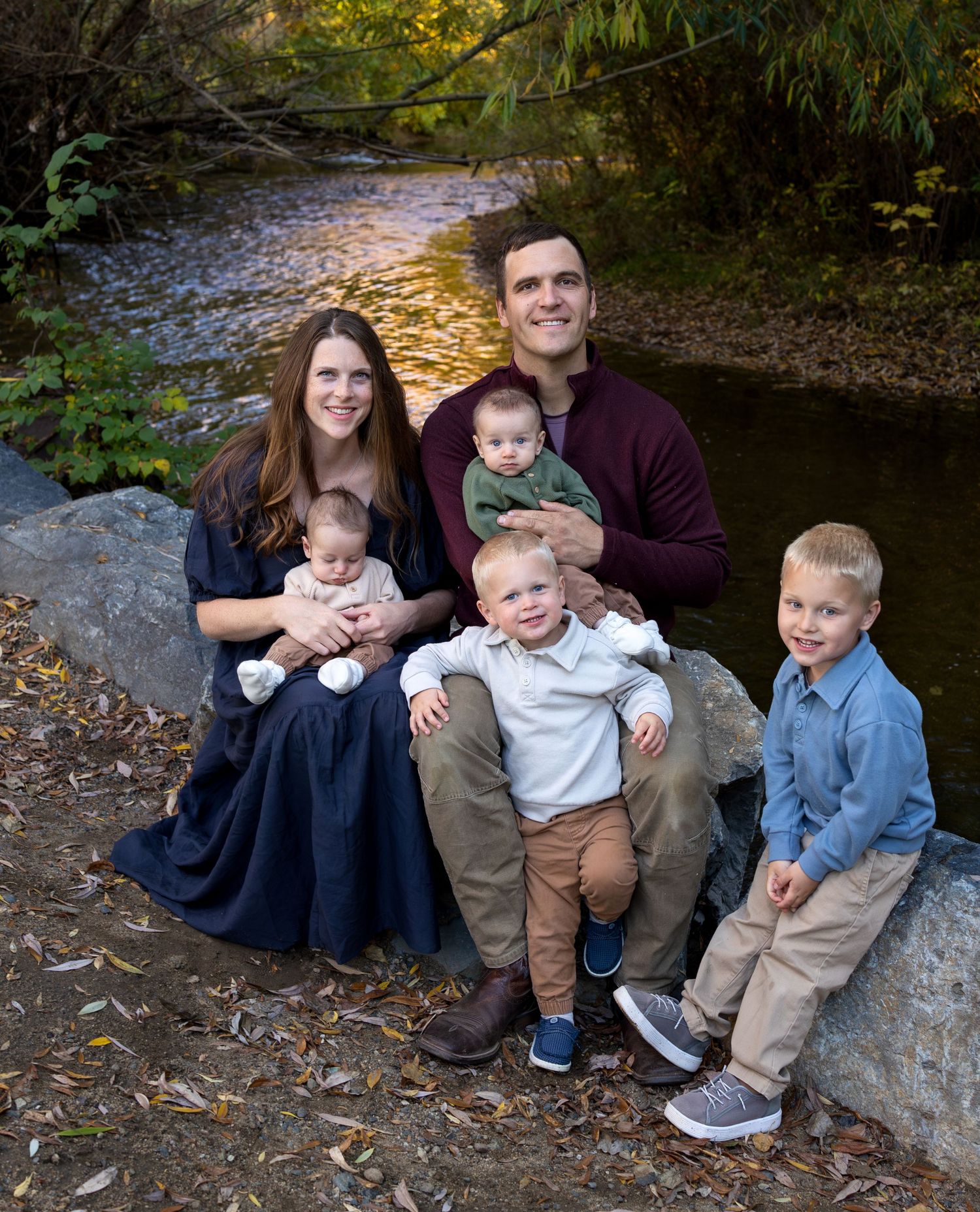 A family sits on a rock ledge in front of a river