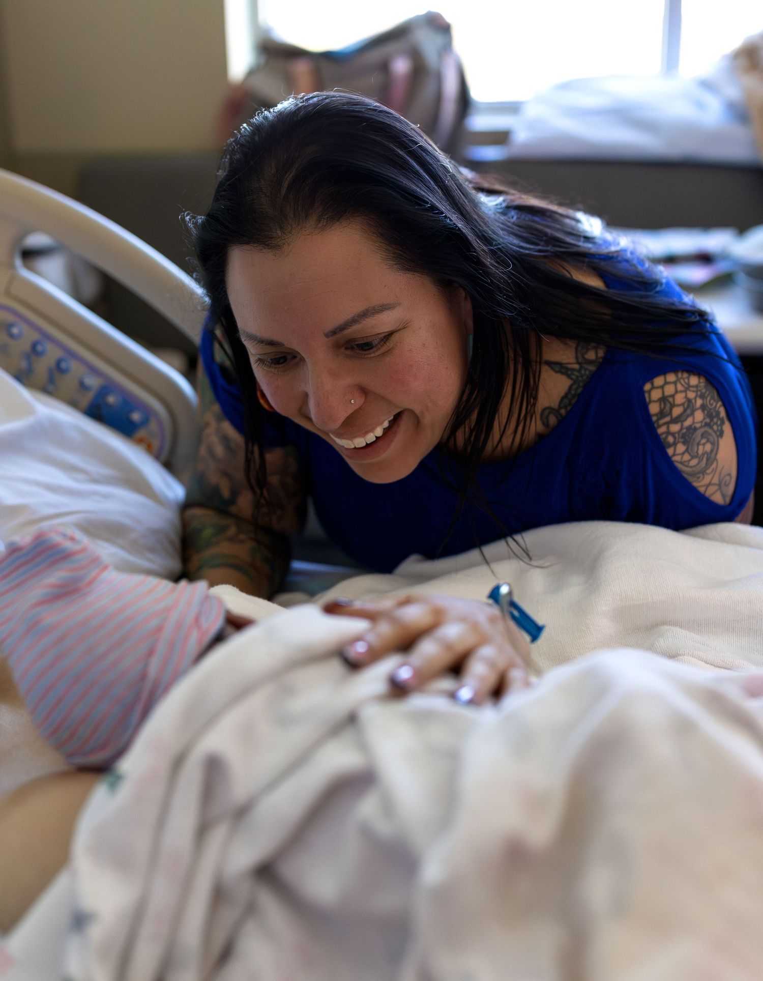 A new Grandmother smiles down on her newborn granddaughter in the hospital.