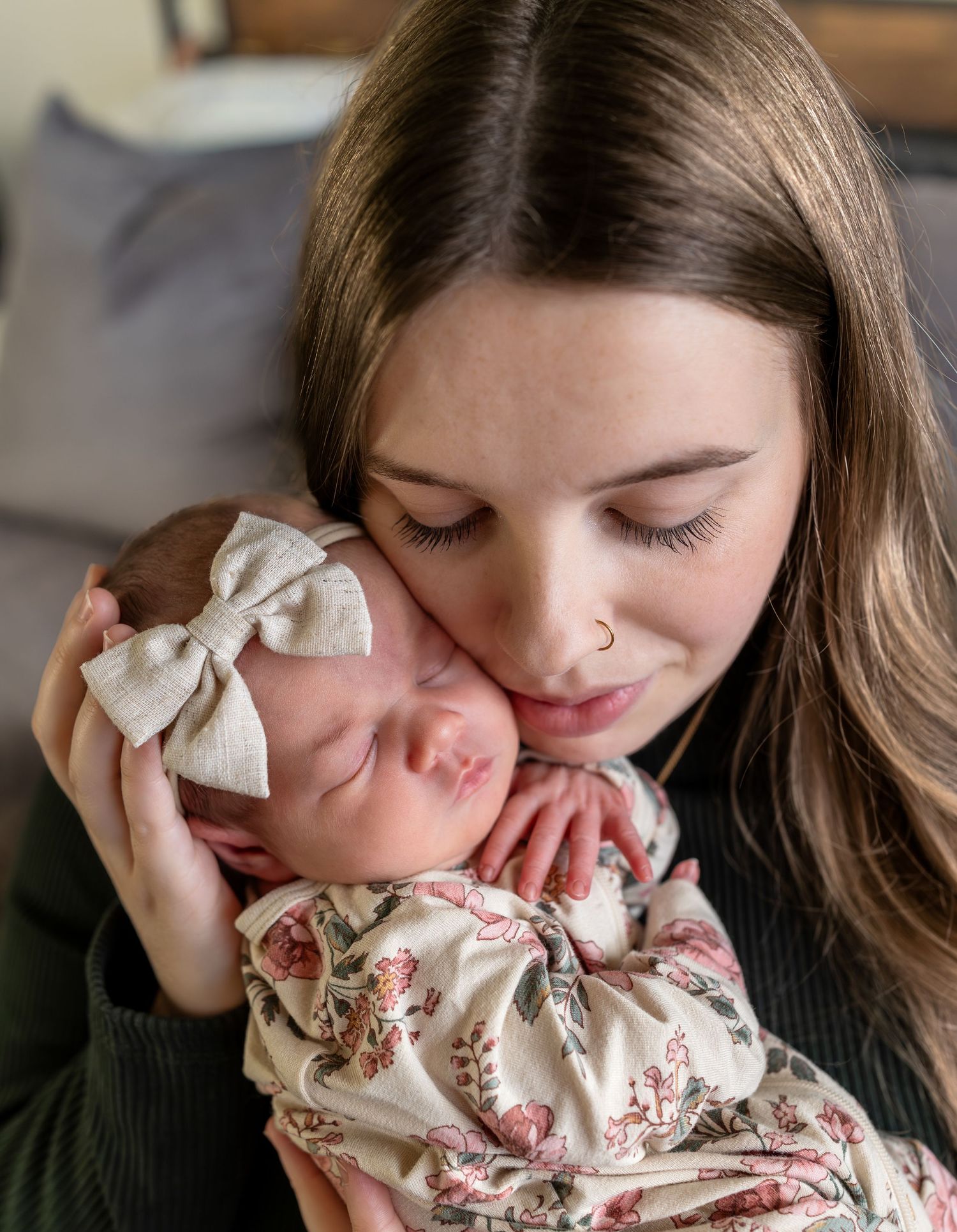 A mom holds her newborn baby girl up to her cheek.