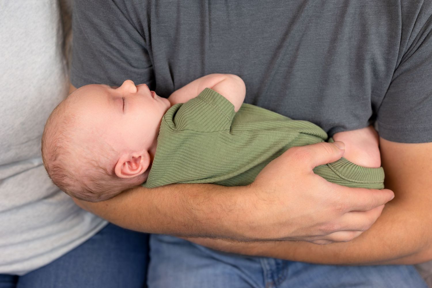 A close up image of a newborn baby boy in his dad's arms.