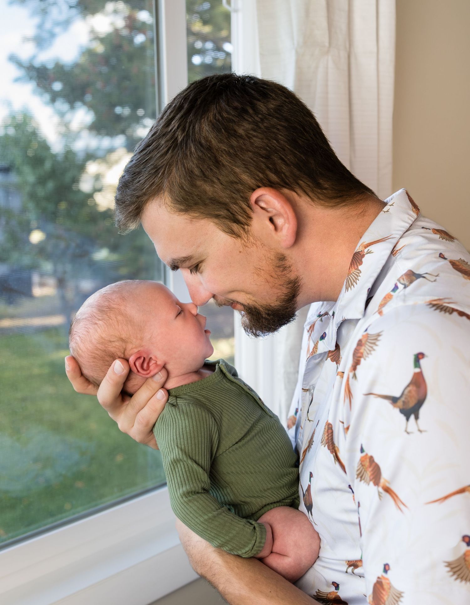 A Dad touches noses with his newborn son in this newborn photoshoot