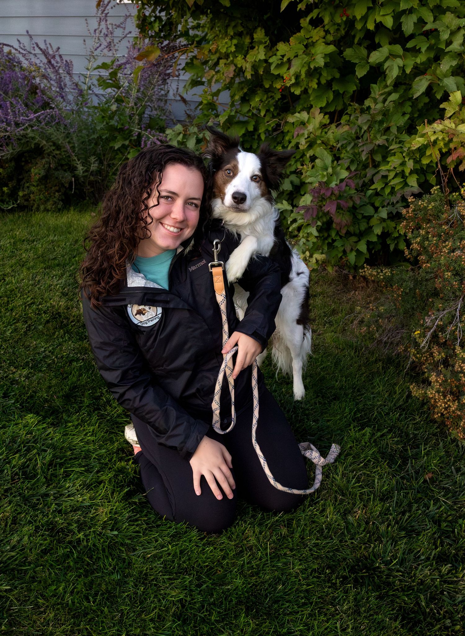 A woman poses with her dog propped on her shoulder