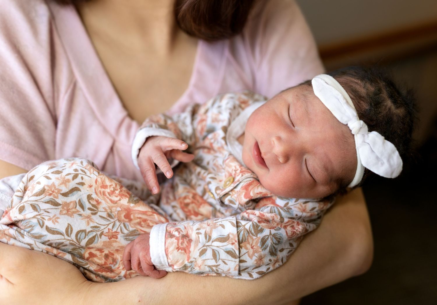 A close up image of a newborn baby girl in her mothers arms