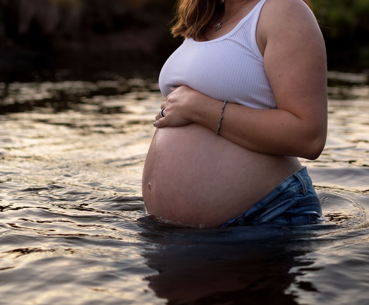 A photo of a pregnant belly half submerged in the water