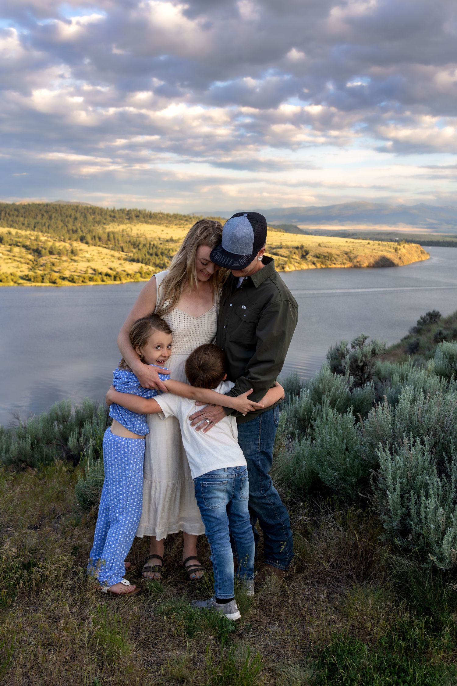 A family embraces each other on a cliffside with a river in the background