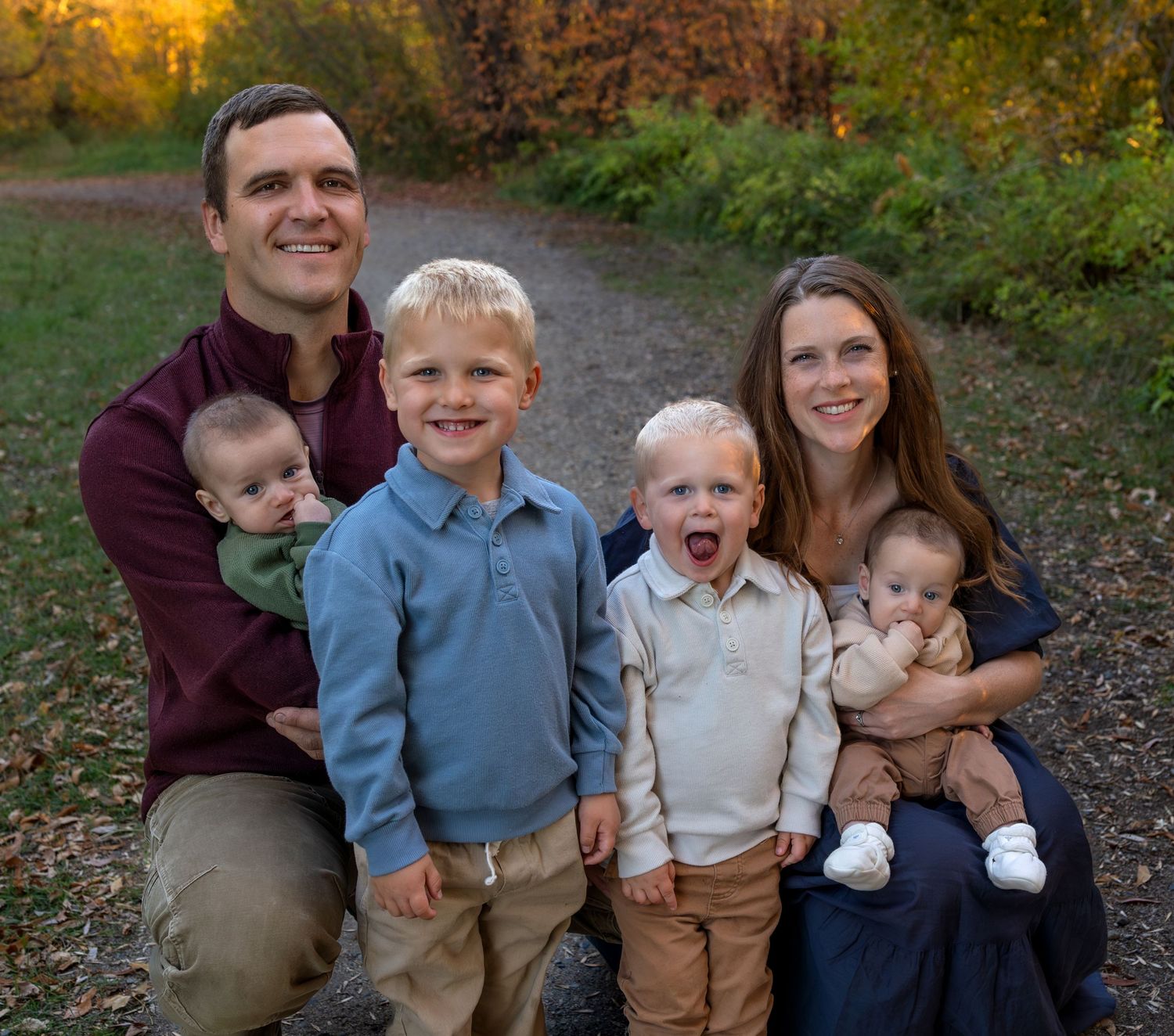 A family portrait on a trail with greenery behind them
