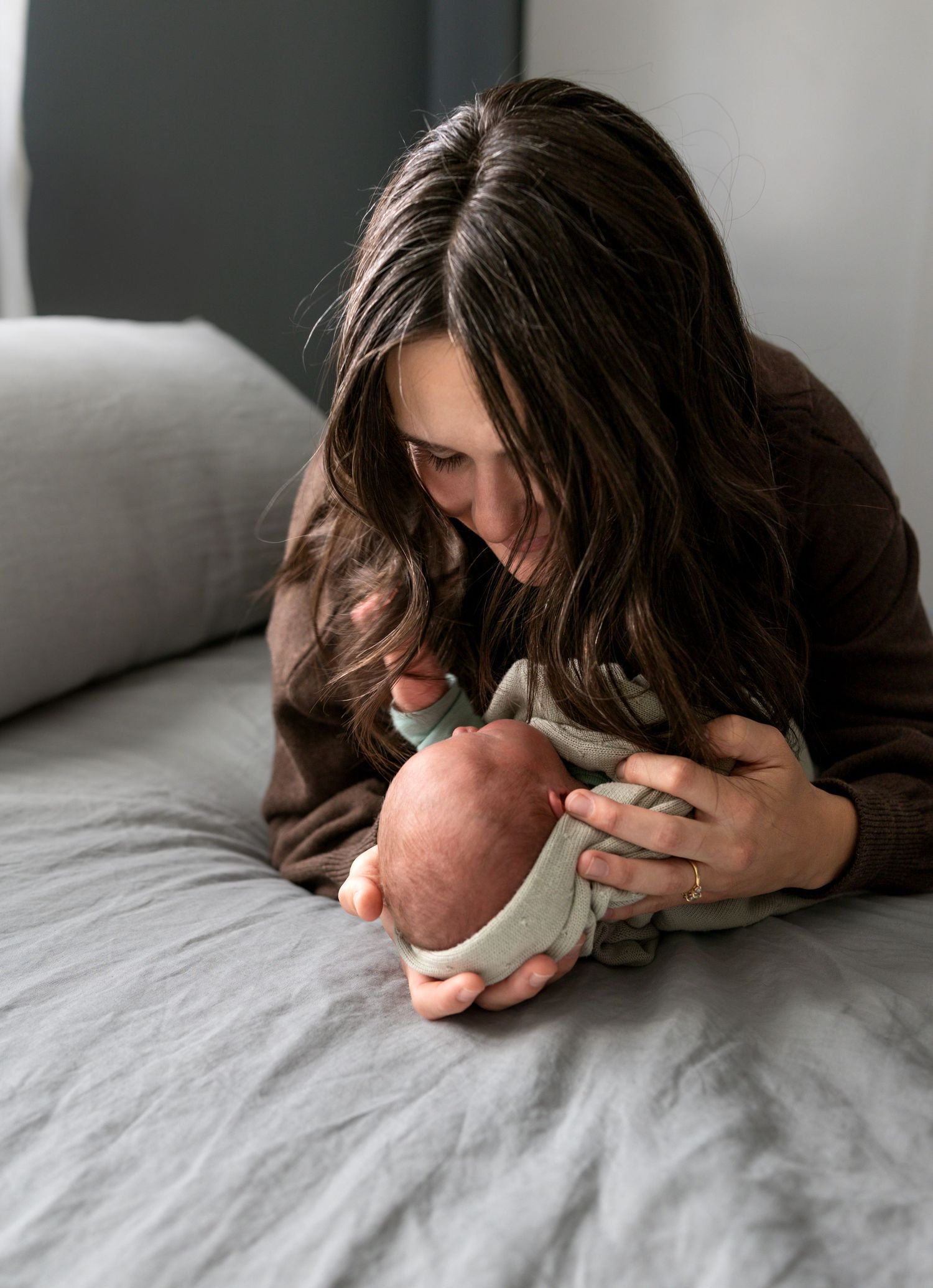 A mother lays on her bed cradling her newborn son