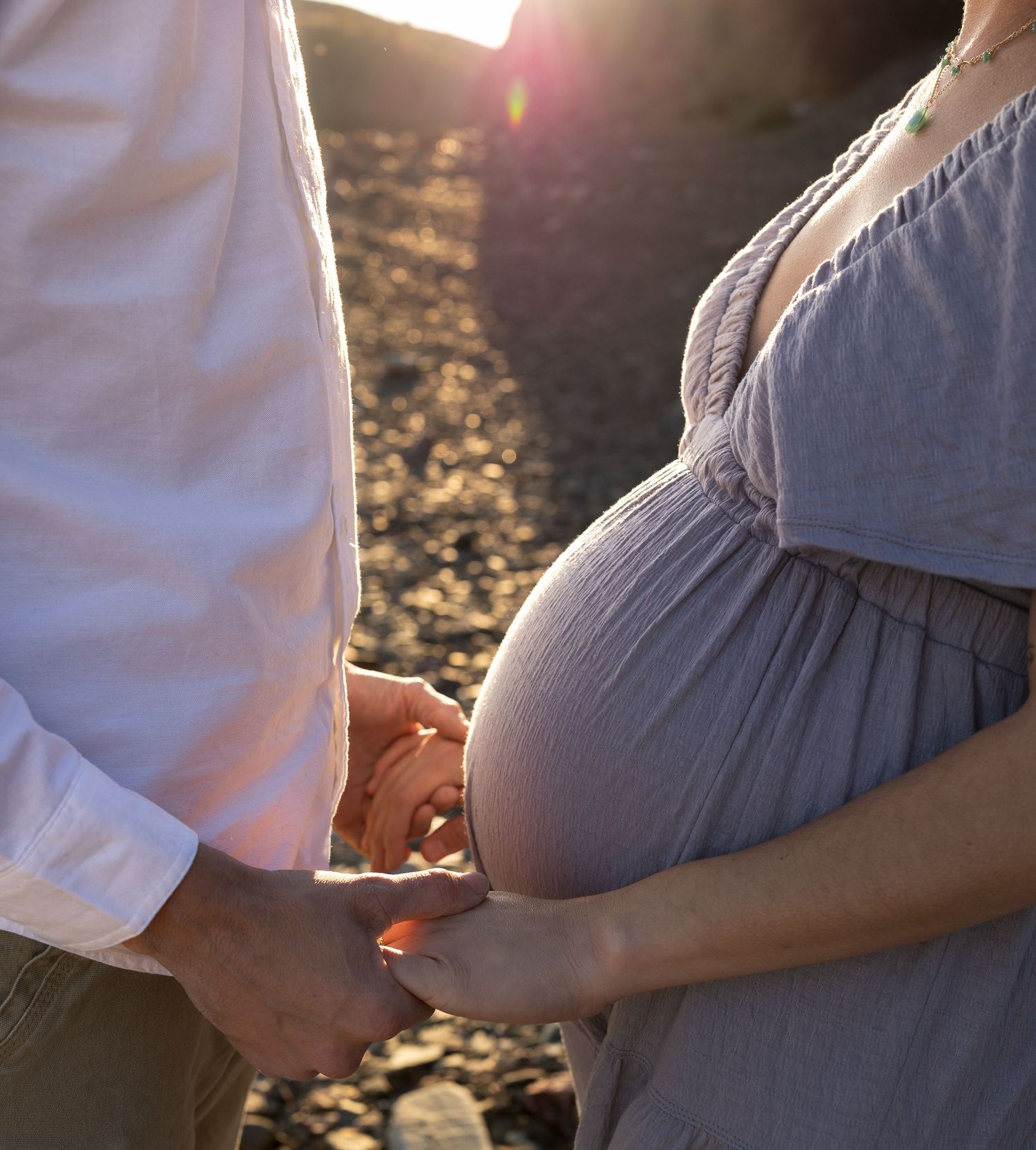 An up close image of a pregnant belly and the mother and father holding hands