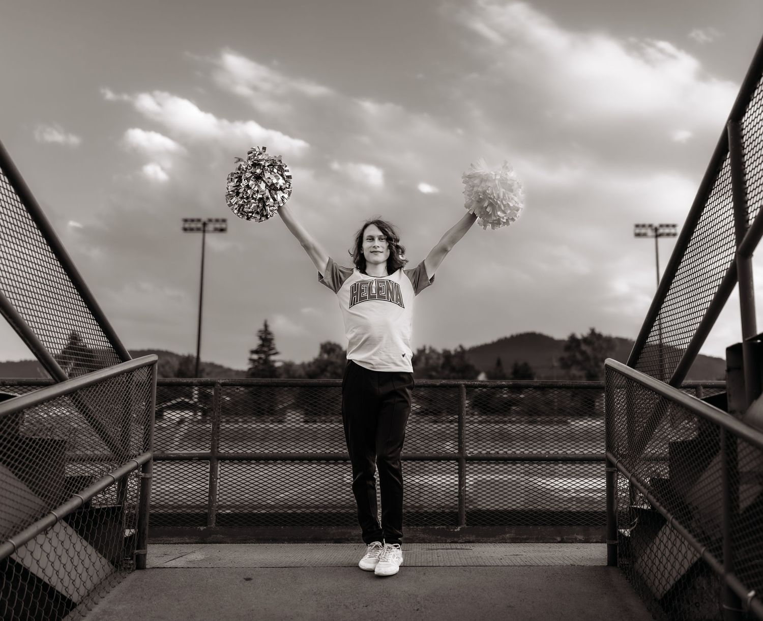 A young man poses in his cheer uniform at a football stadium