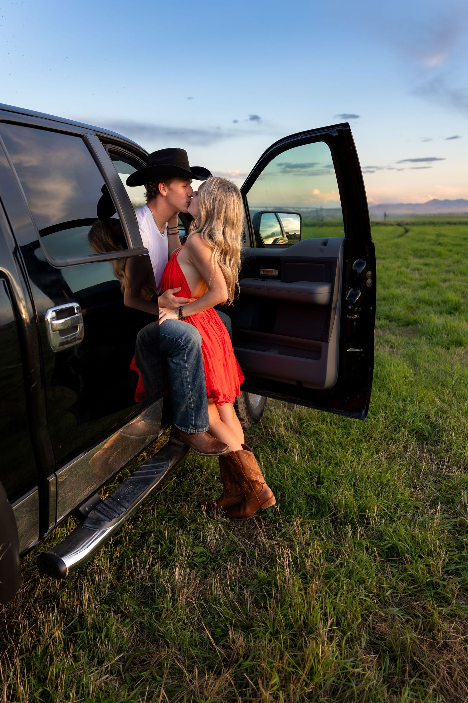 A young couple kiss in a pickup truck in a corn field
