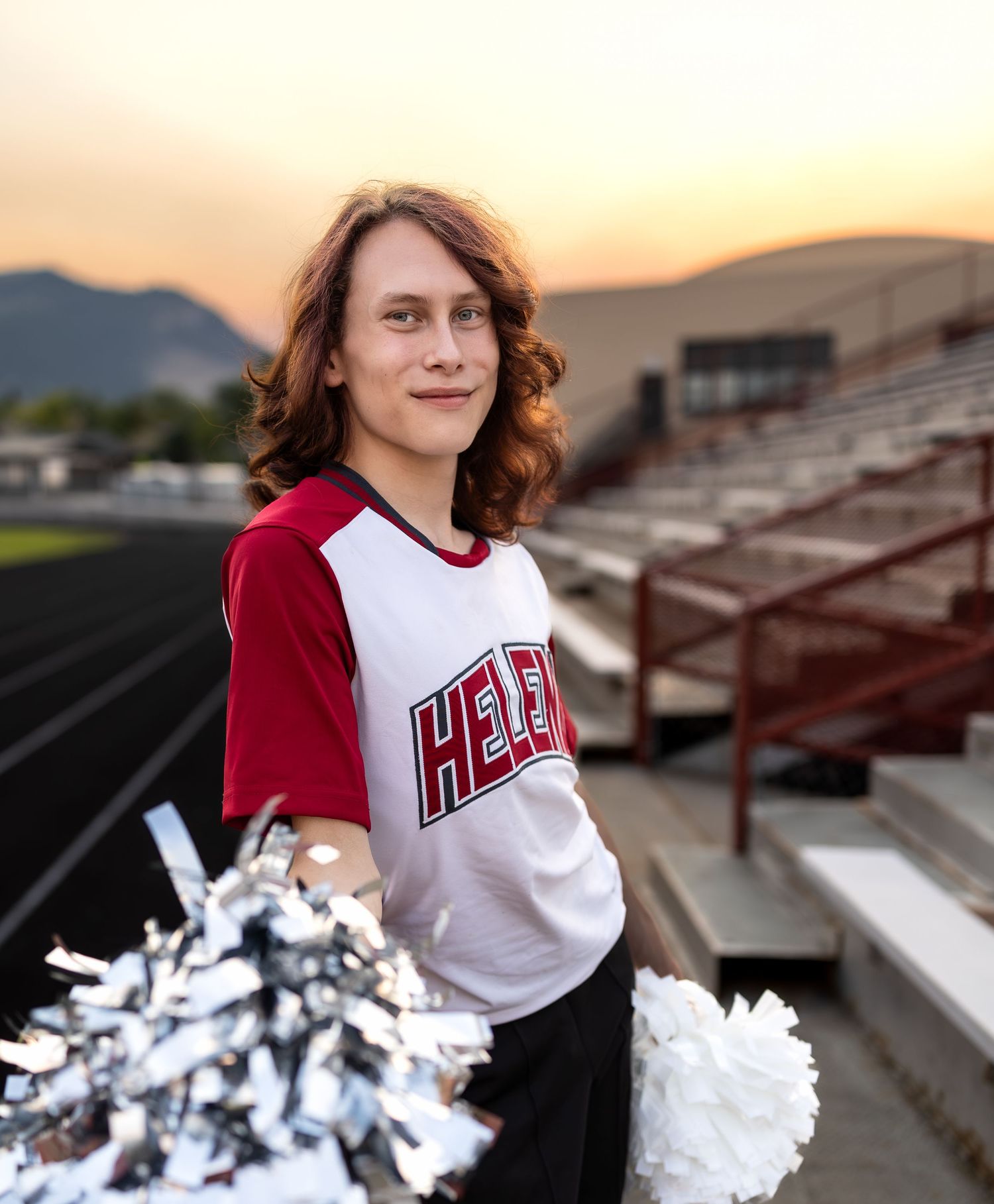 A young man poses for his senior photos at a football field