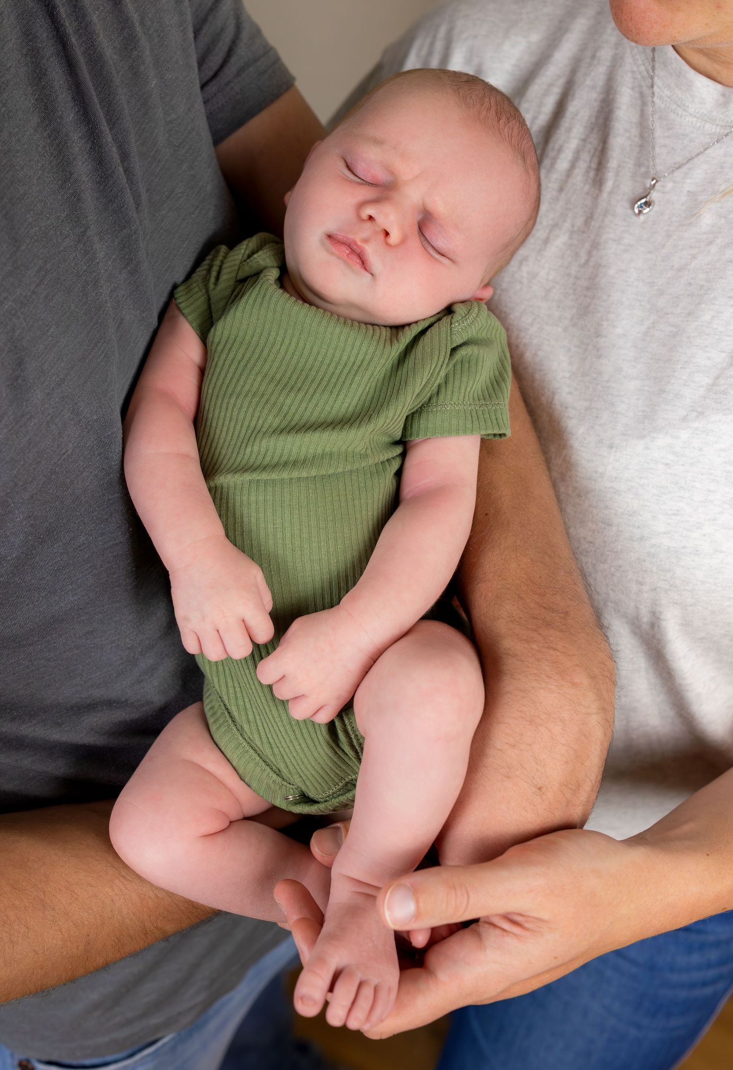 A close up image of a newborn baby boy cradled in his mom and dad's arms.