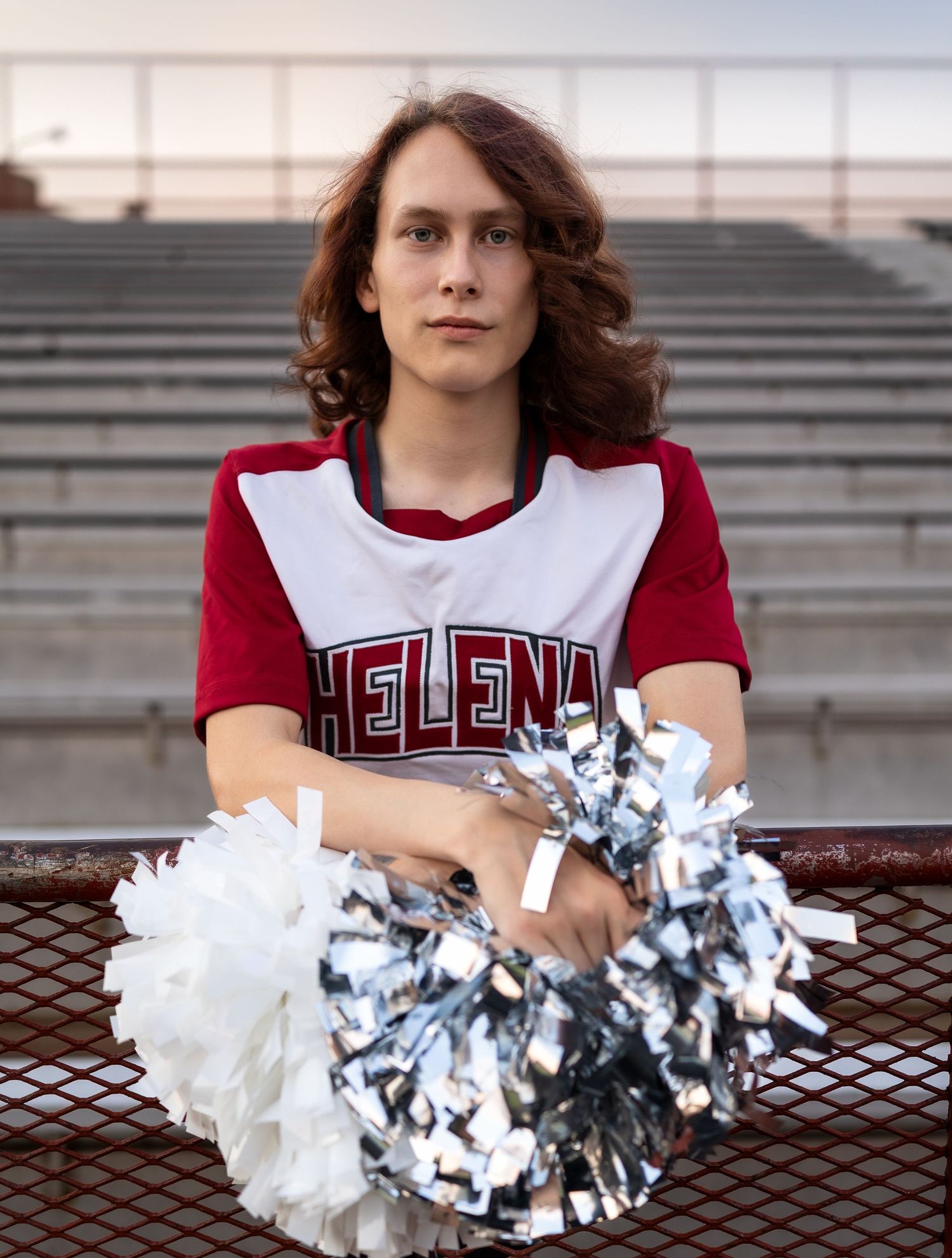 A young man poses in his cheer uniform in the bleachers