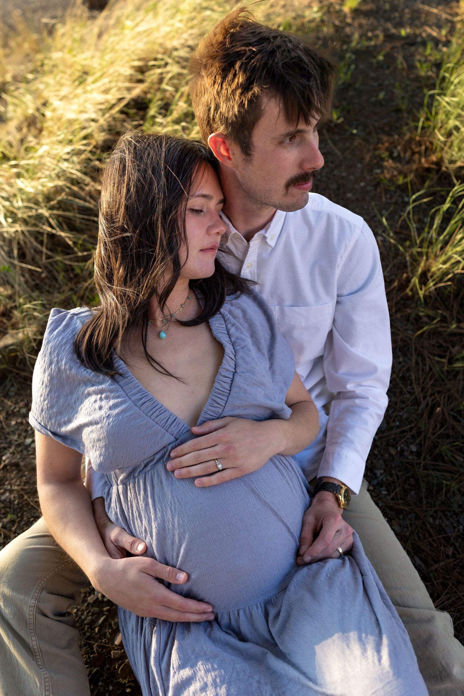 A pregnant woman leans against her husband