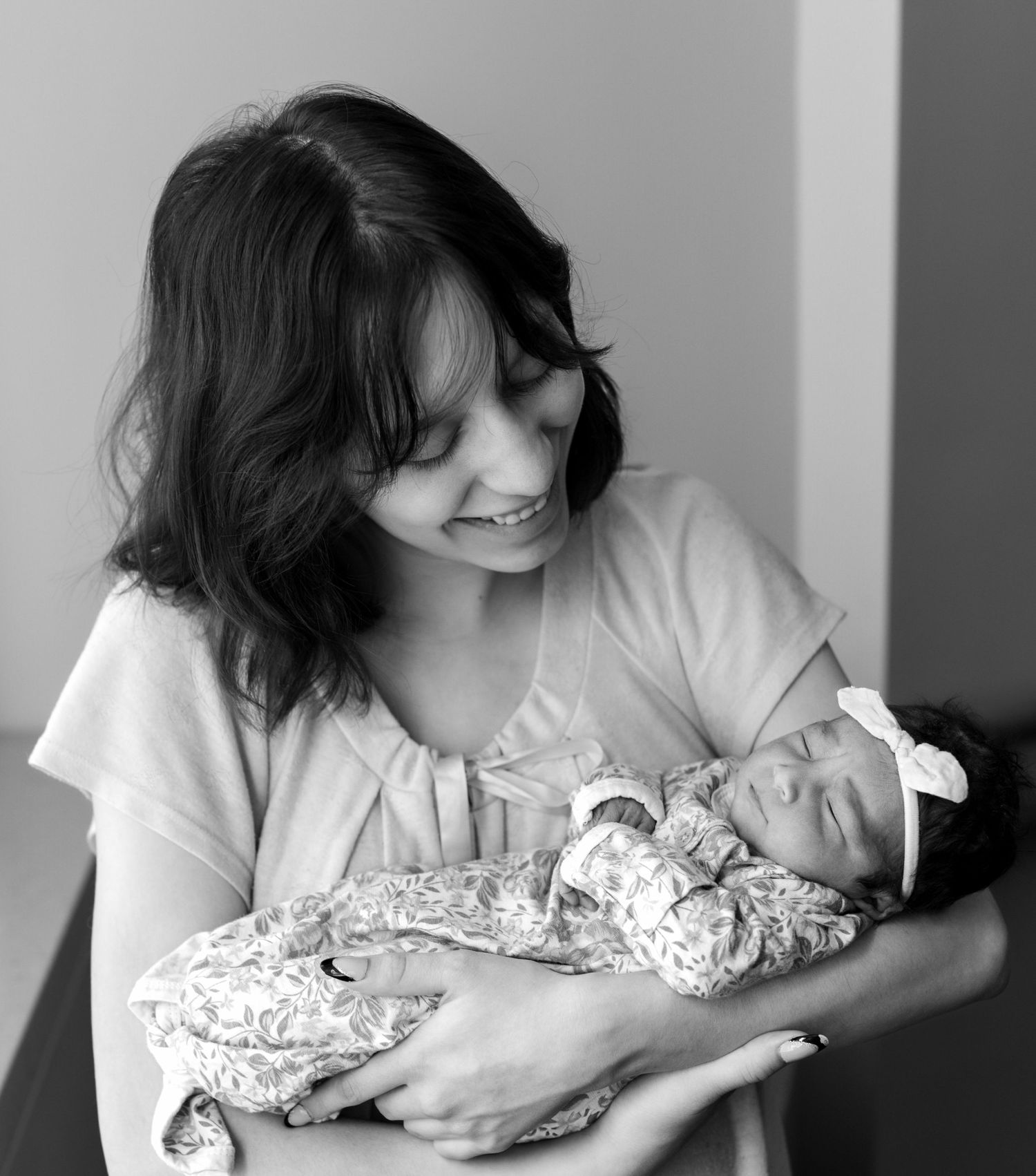 A new mother smiles down at her new baby daughter in the hospital