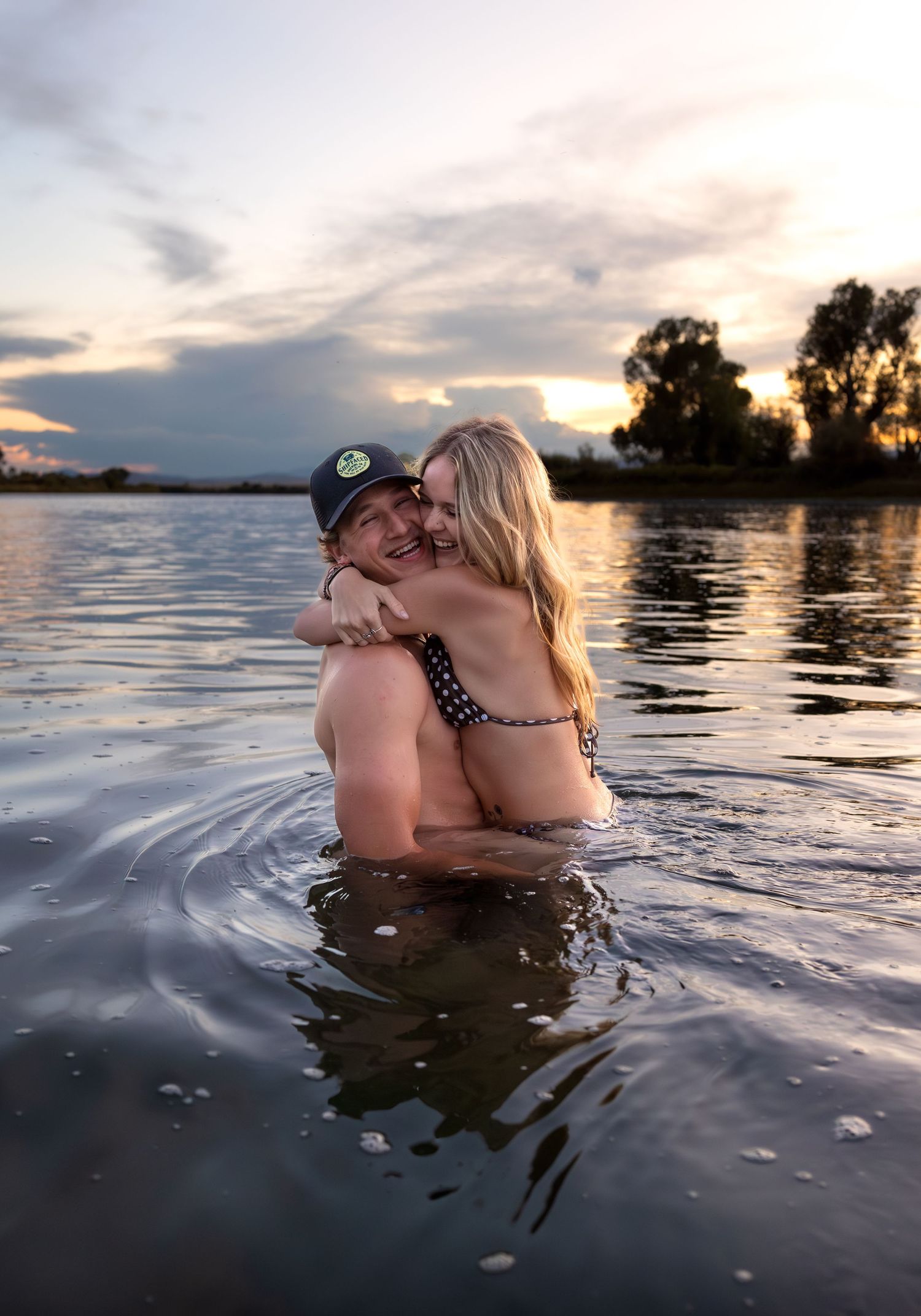 A young couple embrace in the river at sunset