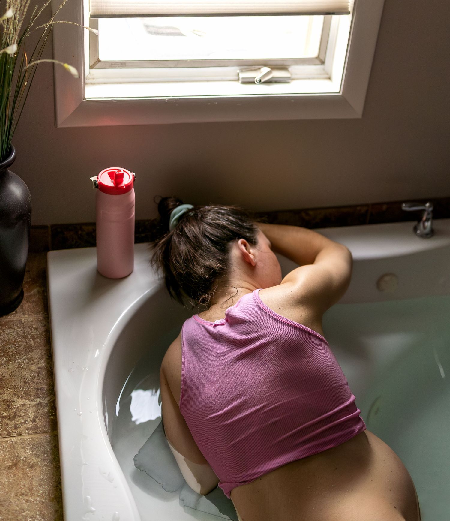 A laboring woman rests her head against the bath tub during contractions