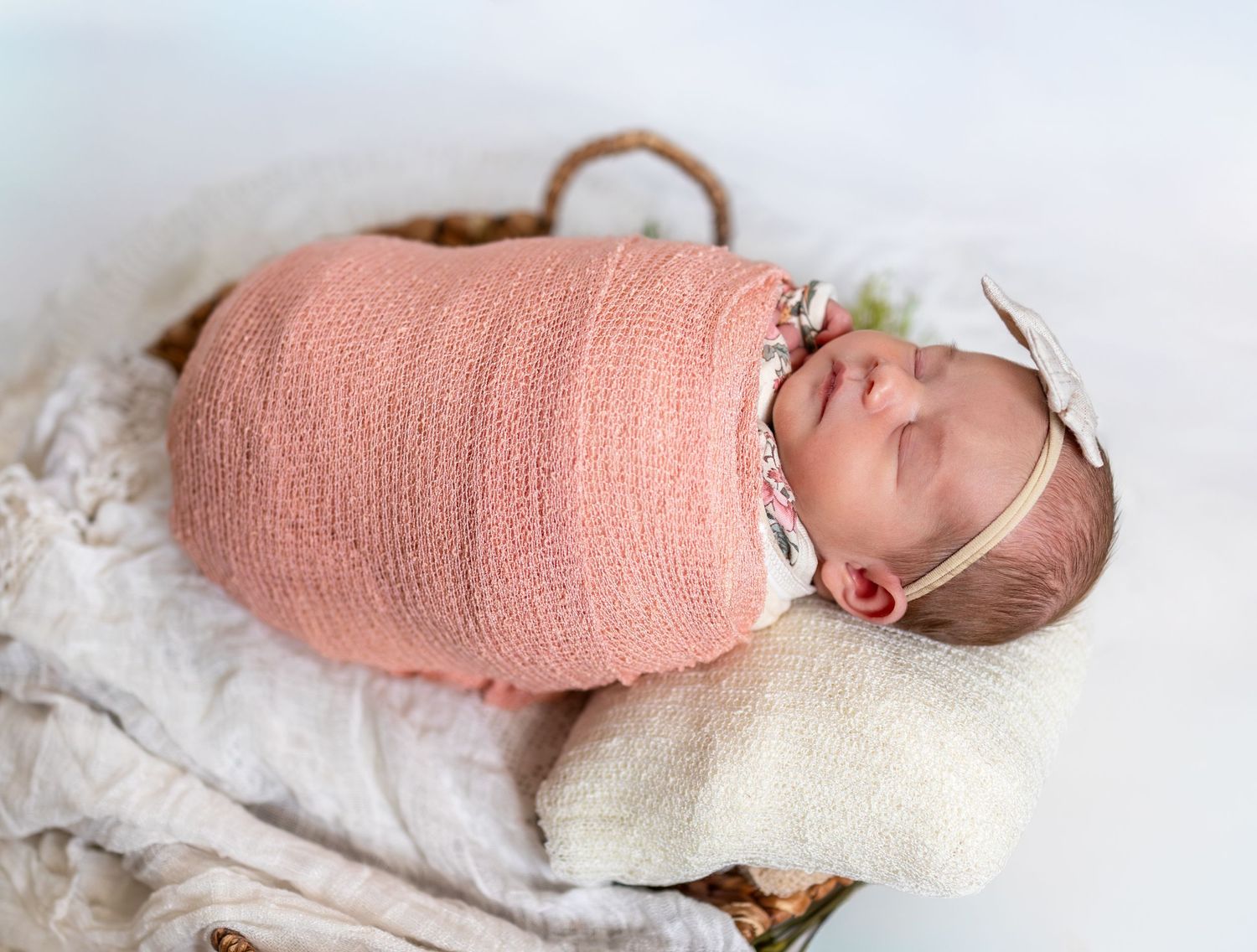 A posed photo of a newborn baby girl wrapped in a pink wrap.