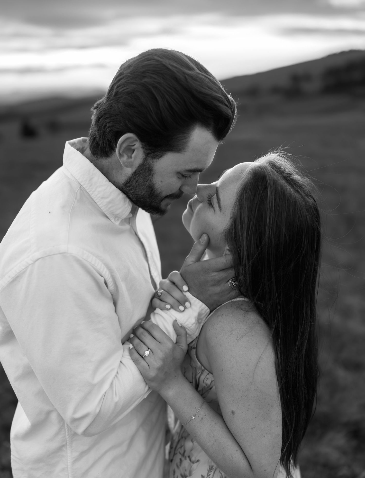 A black and white image of a couple about to kiss, the mans hand holding the woman's face.