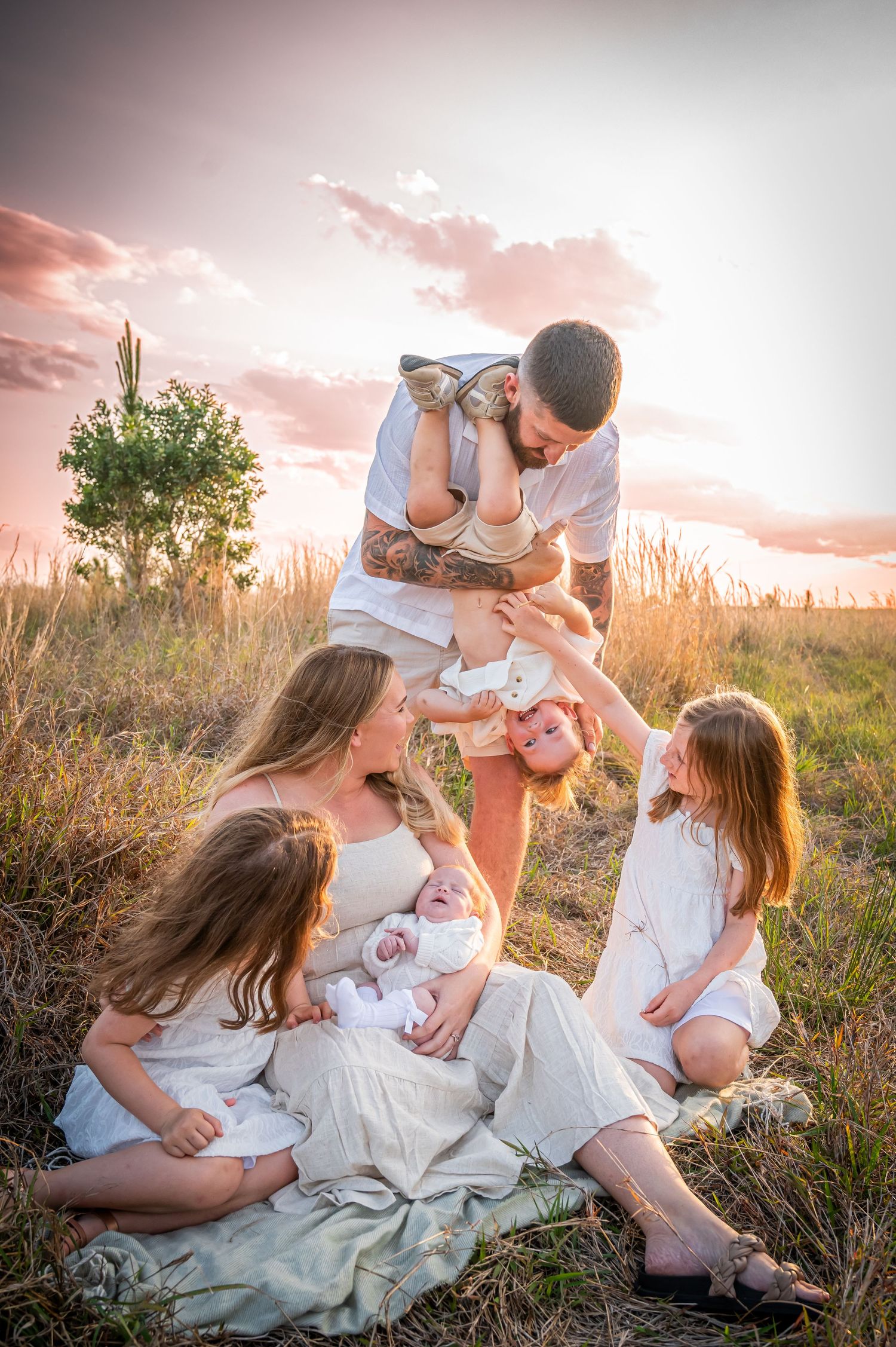 Family enjoying playful moment together in golden sunset field.