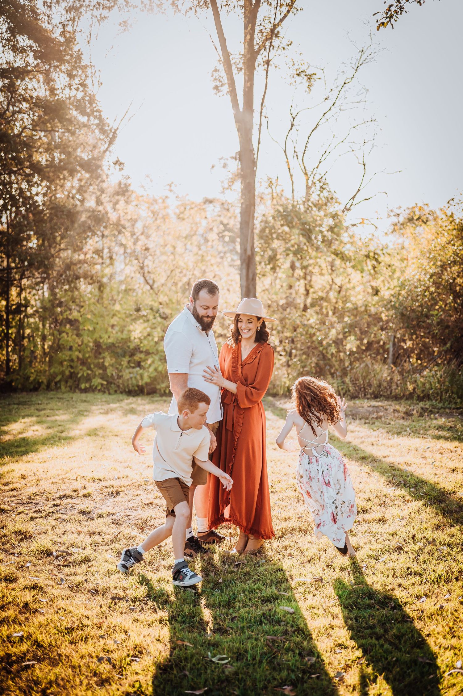 Family plays together in sunlit garden during golden hour photo session.