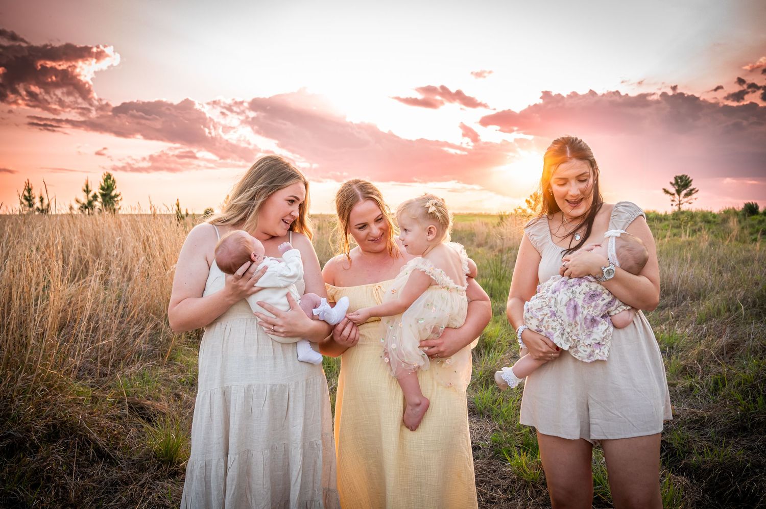 Group in white dresses gathered in field during pink sunset.