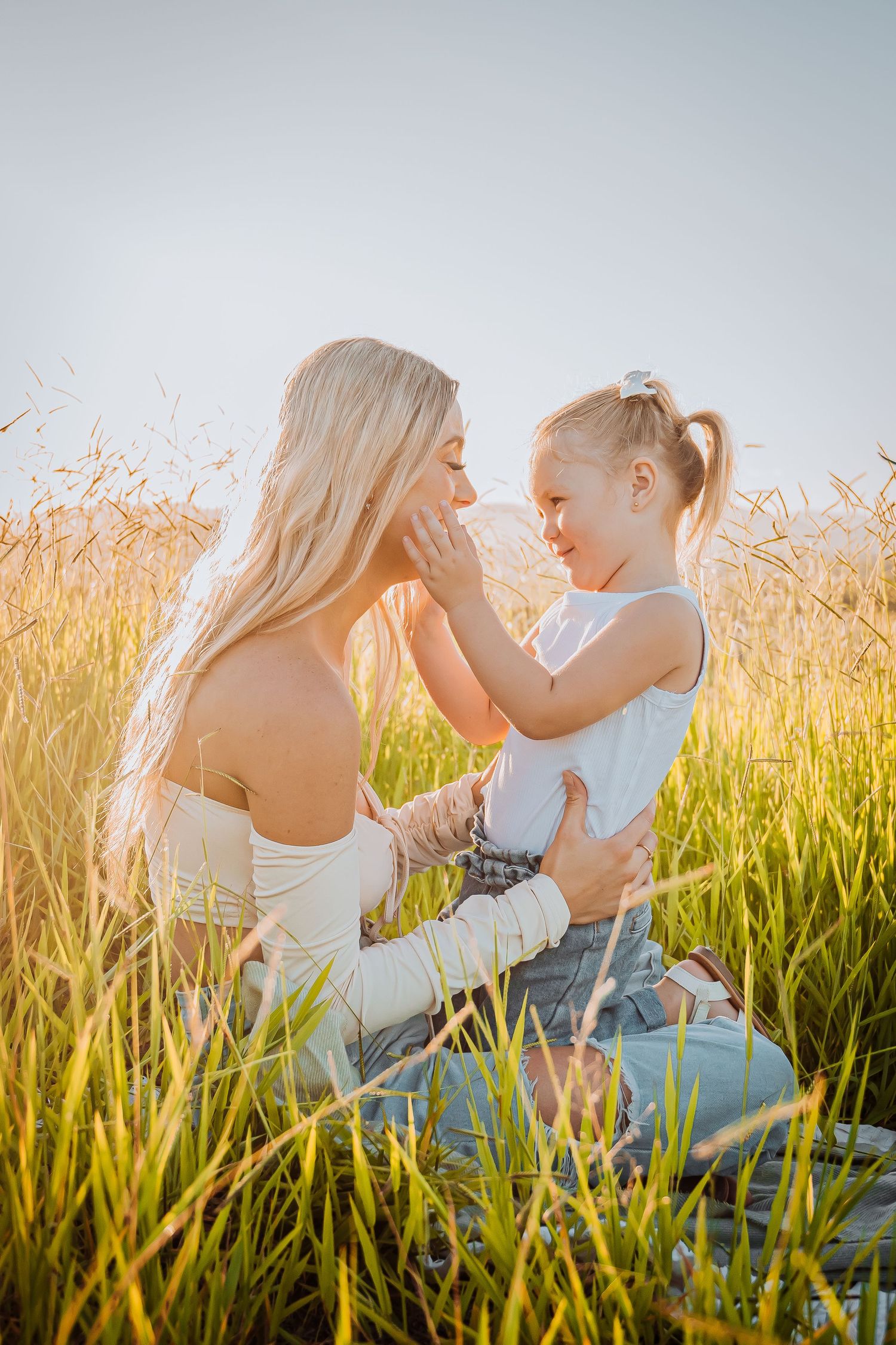 Sweet outdoor portrait session with people touching faces while sitting in golden meadow grass.