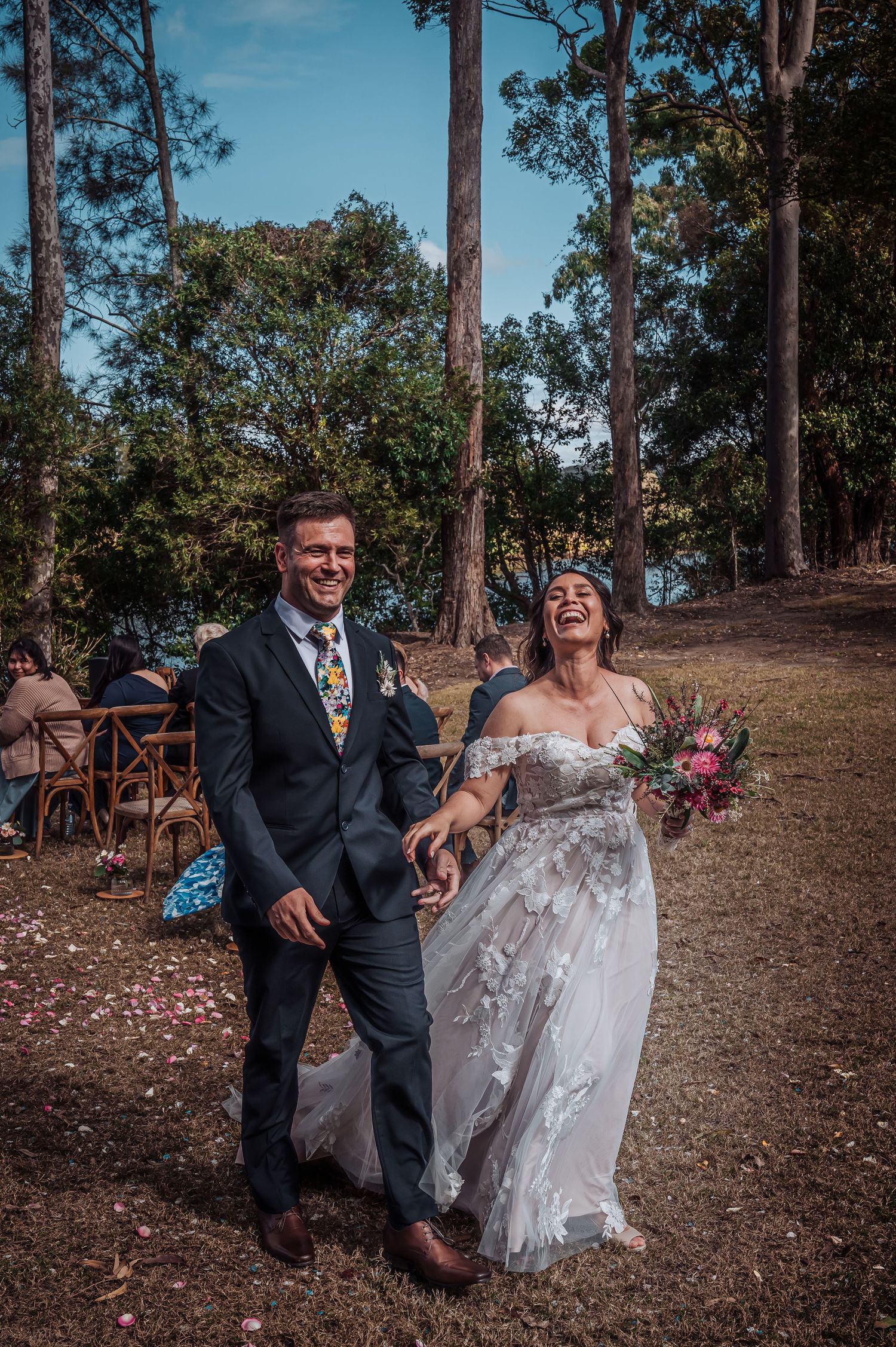 Joyful wedding couple walking down a forest path after their ceremony.
