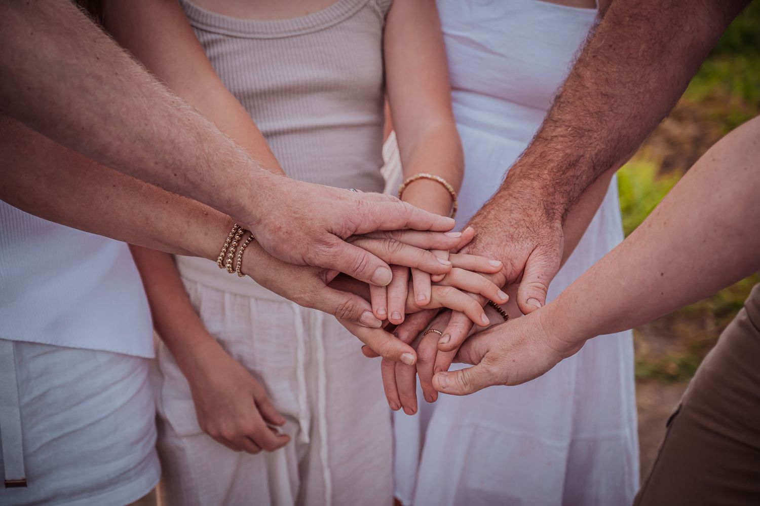 Multiple hands coming together in unity, stacked on top of each other against a light background.